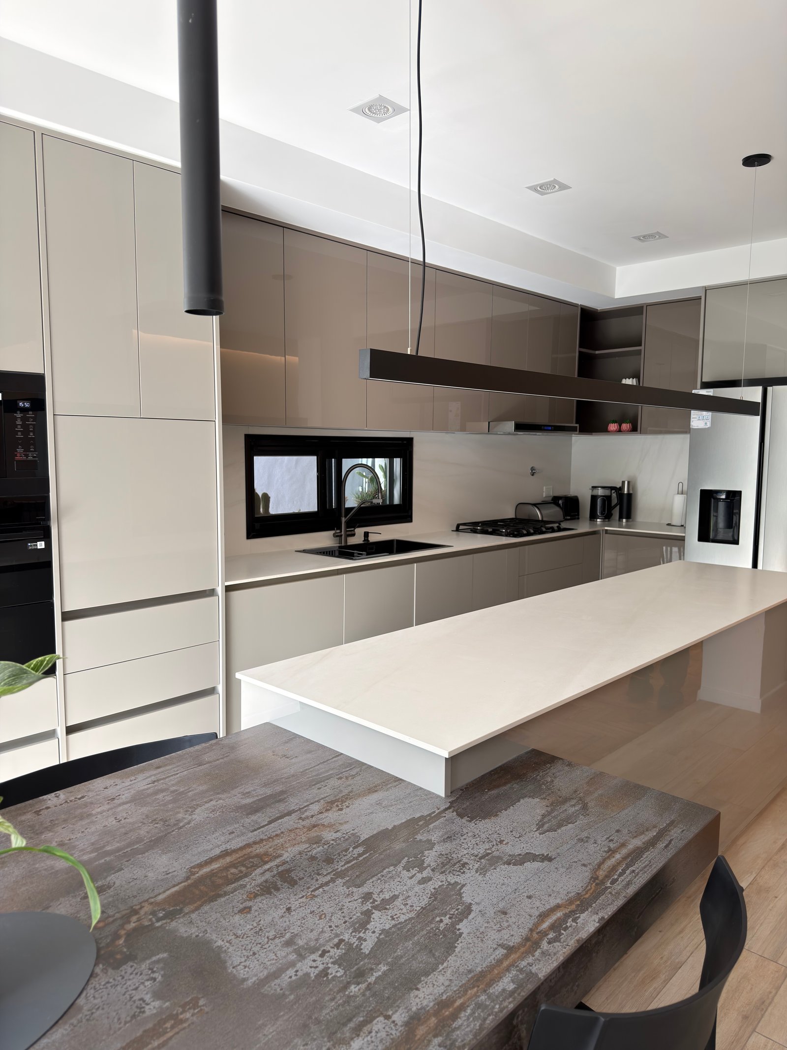 Cocina moderna con isla blanca, muebles beige y contraste de piedra — proyecto italia 2, por Estudio Grupo 32, en Vicente López