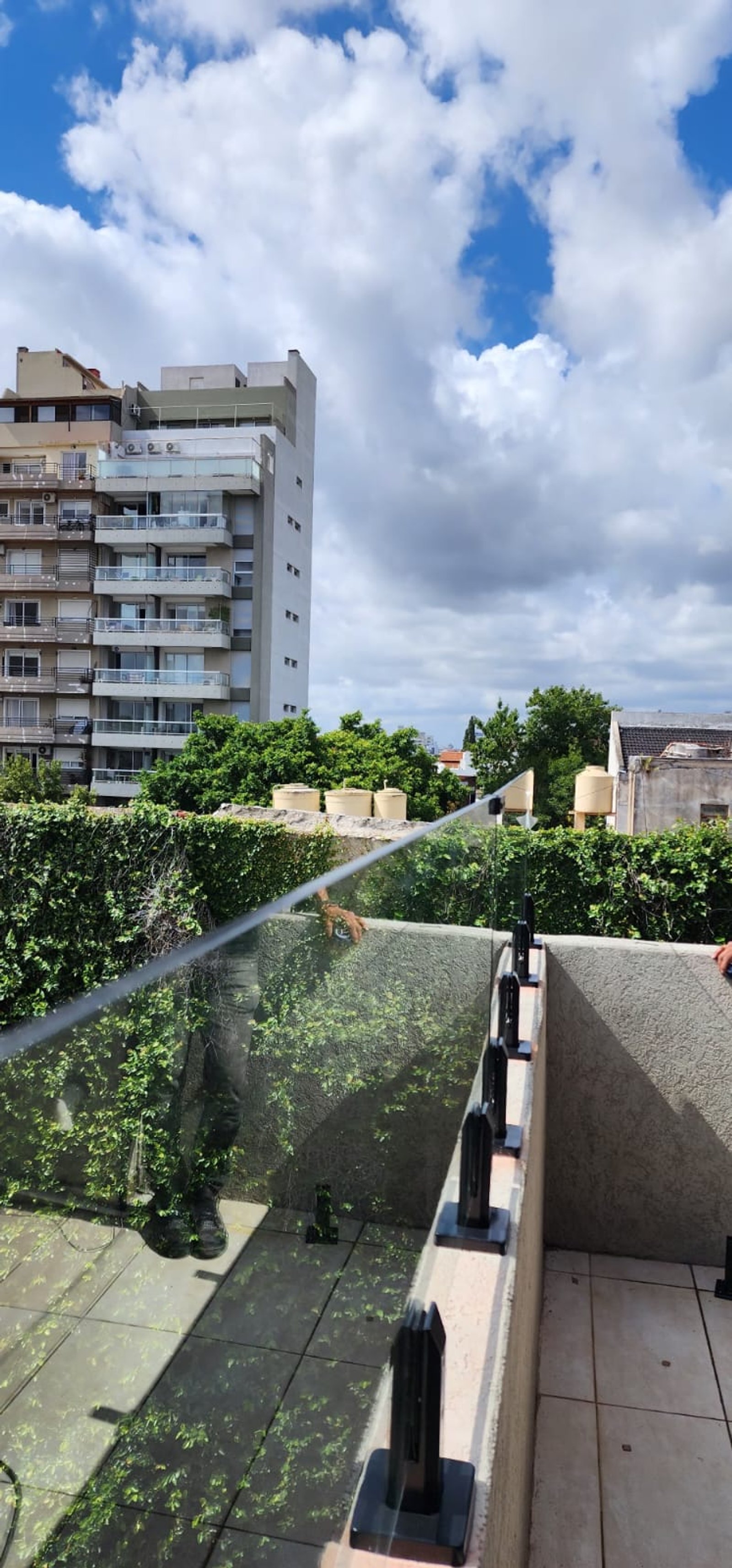 Terraza de balcón moderna con pared verde y baranda de vidrio — proyecto Baranda templada con pinzas, por Cristalcenter, en Villa Luro