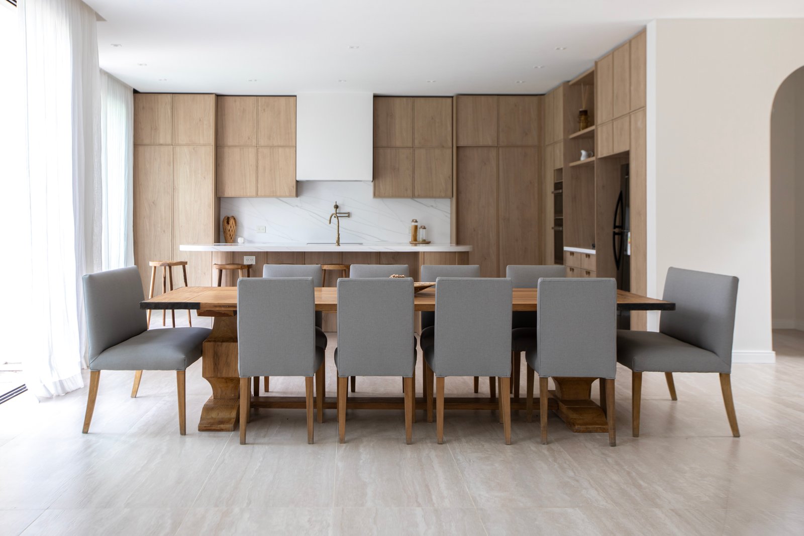 Comedor y cocina modernos de planta abierta con isla y detalles en madera — proyecto OBRA TRAVERTINO BEIGE, por ILVA, en Provincia de Buenos Aires
