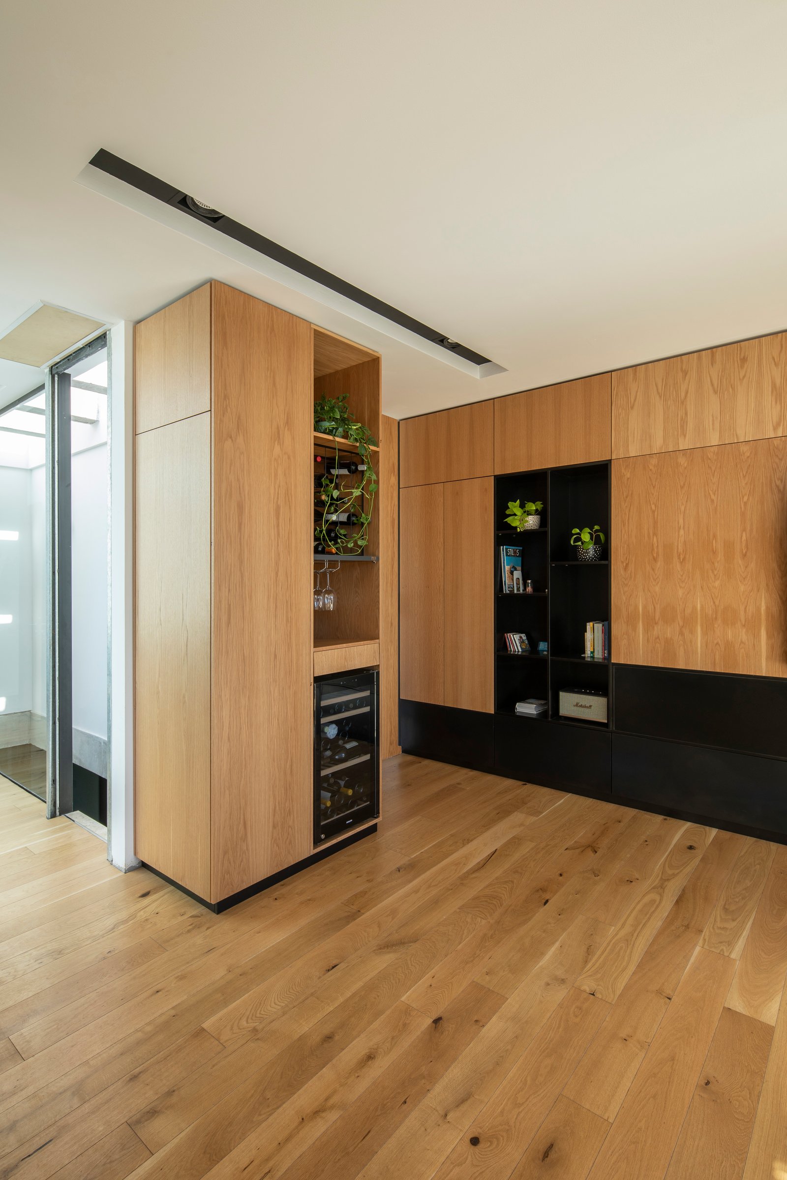 Living moderno con muebles de madera y estanterías negras — proyecto Casa MECHA, por Grupo CRBN, en B1712 Castelar