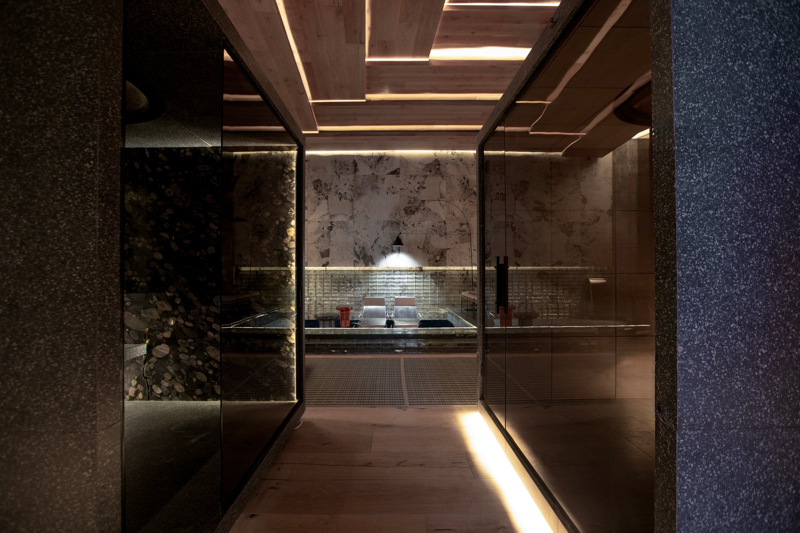 Pasillo moderno con iluminación indirecta y paredes de piedra — proyecto Casa Foa Madero Harbour, por Vite Porcellanato, en Buenos Aires