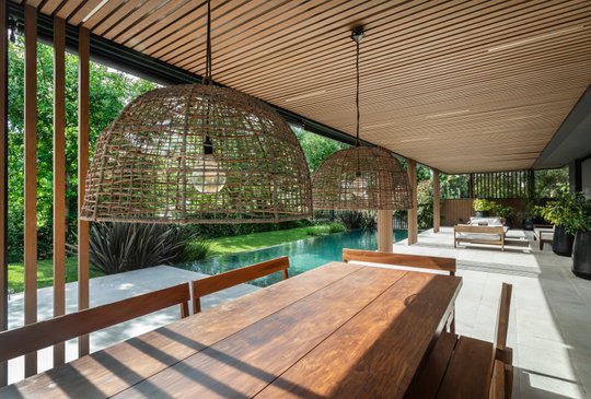 Comedor exterior con lámparas de mimbre y techo de madera — proyecto Obra Kahala, por lifecycle, en City Bell