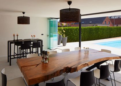 Comedor moderno con mesa madera y vista a pileta exterior — proyecto QUINCHO - PARRILLA , por CERRAMIENTOS PANORAMICOS, en Canning