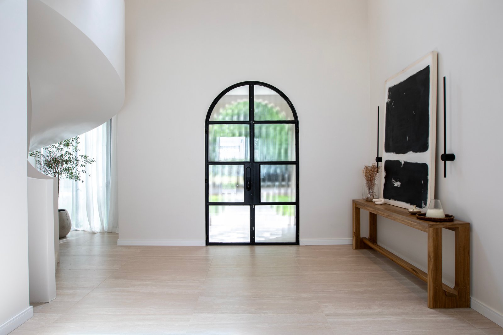 corredor moderno com porta preta em arco — projeto OBRA TRAVERTINO BEIGE, por ILVA, em Provincia de Buenos Aires