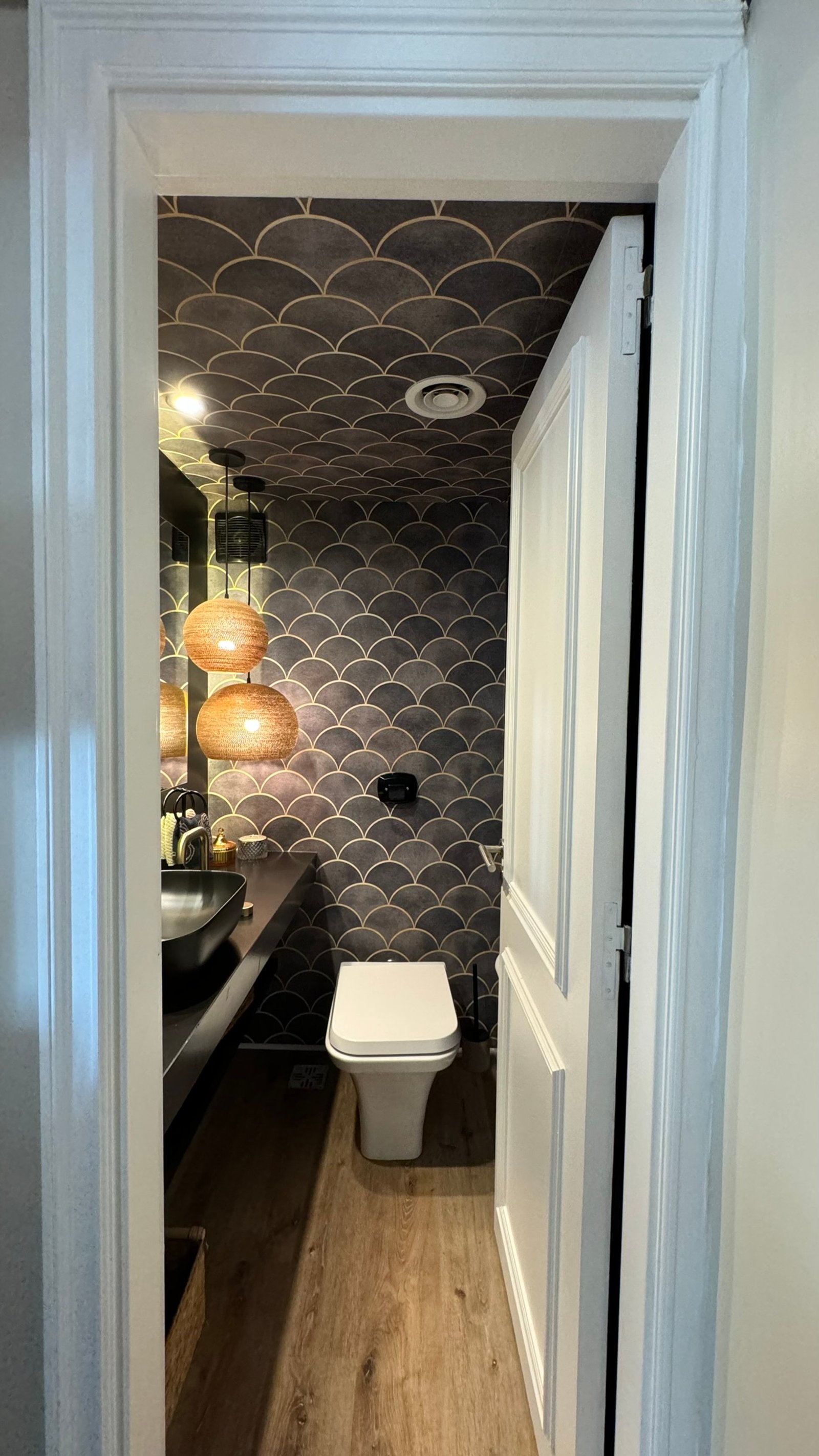 Baño pequeño con papel tapiz de escamas, lavabo oscuro y dos lámparas colgantes — proyecto Coronel Diaz, por MDBK Arquitectura, en Palermo