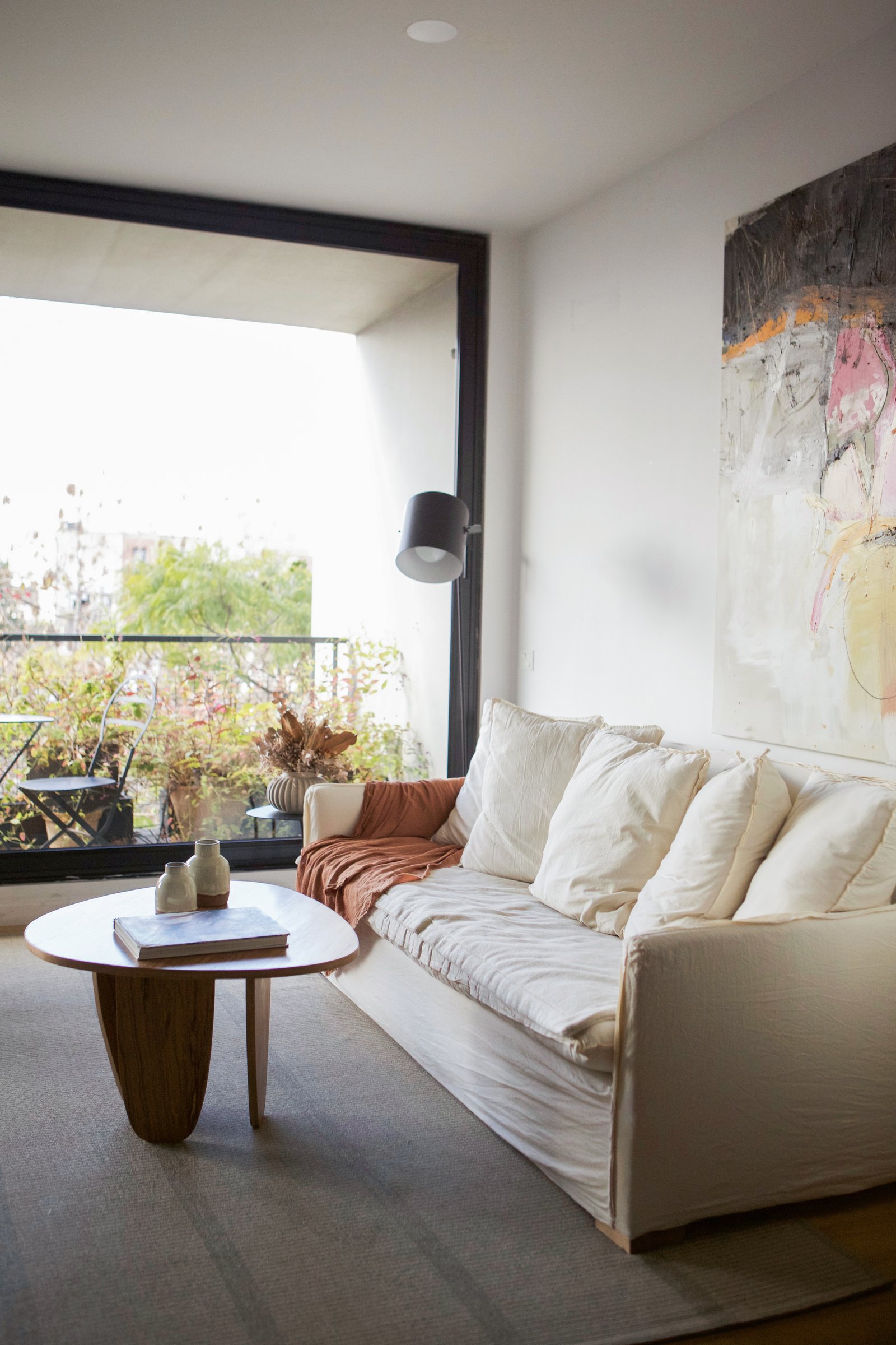 Sala de estar moderna con sofá crema y arte abstracto sobre alfombra gris — proyecto nuñez, por LACROZE DESIGN STUDIO, en Núñez