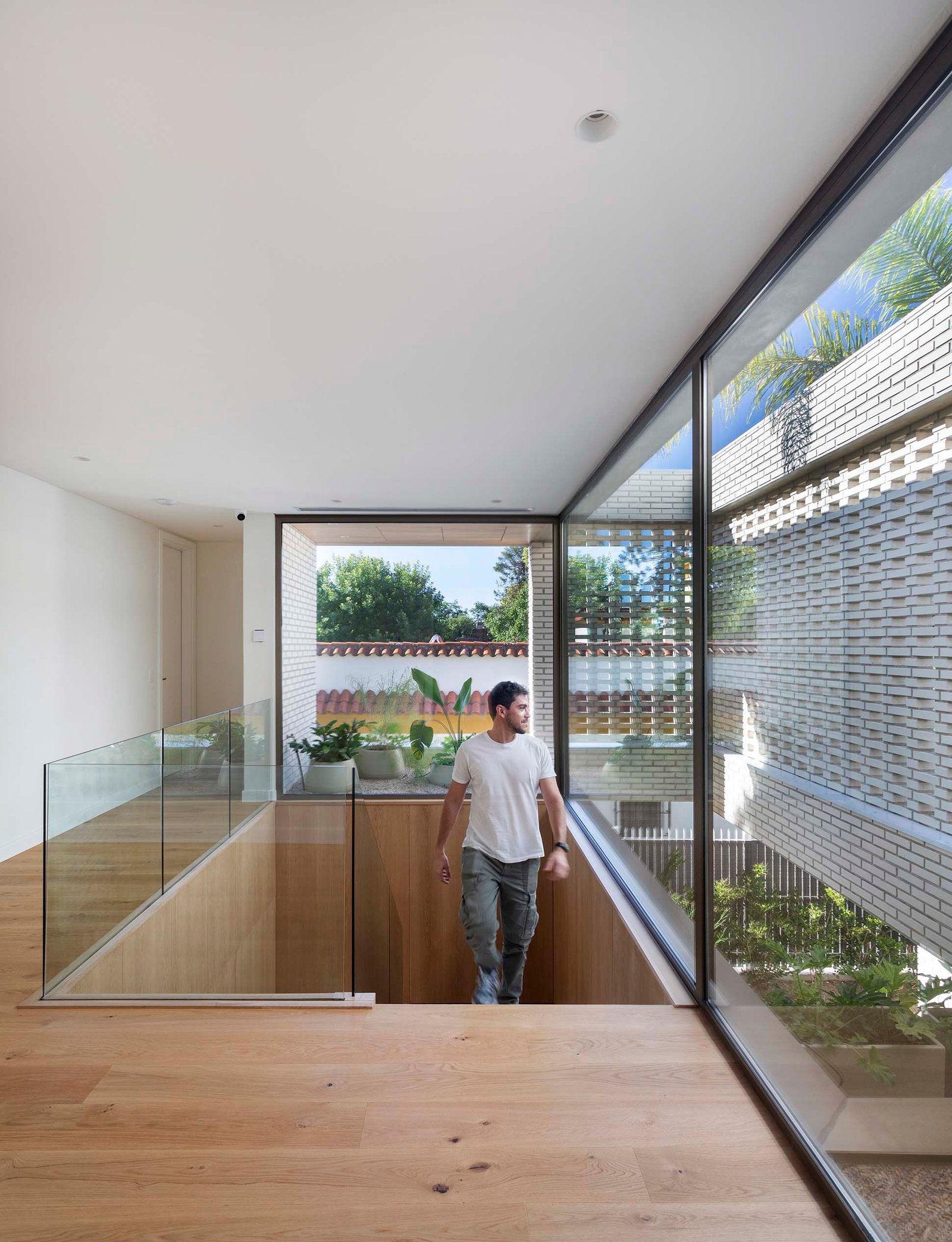 Escada moderna com corrimão de vidro e muita luz natural — projeto Casa Magnolia, por Estudio PK, em San Isidro