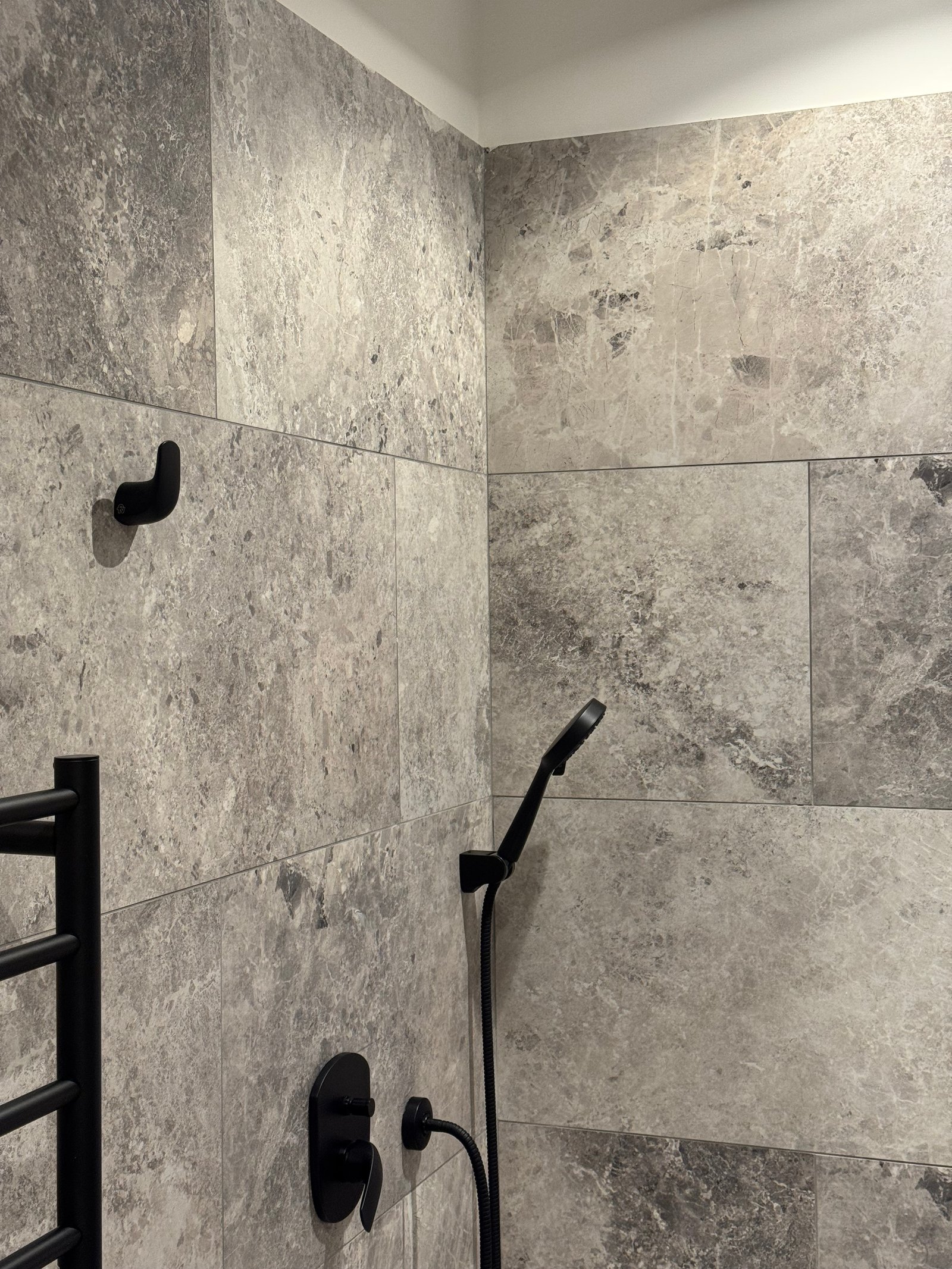 Baño moderno con azulejos de piedra gris y accesorios negros — proyecto CASA LEAN, por Estudio Grupo 32, en Vicente López