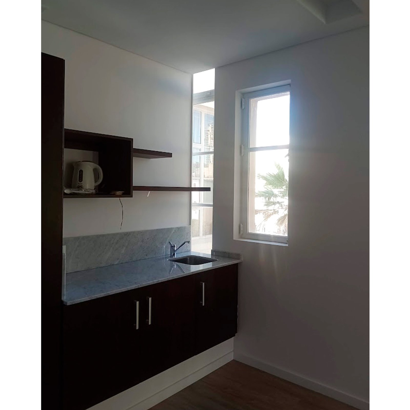 Cocina compacta con gabinetes de madera oscura y encimeras de piedra — proyecto PH Moreno, por ASIA - arquitectura, en San Telmo