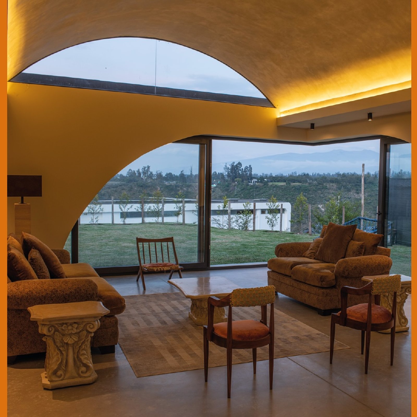 Sala de estar com teto curvo e vista para o campo — projeto Casa Lumbre, por MUCHTEK, em Tumbaco