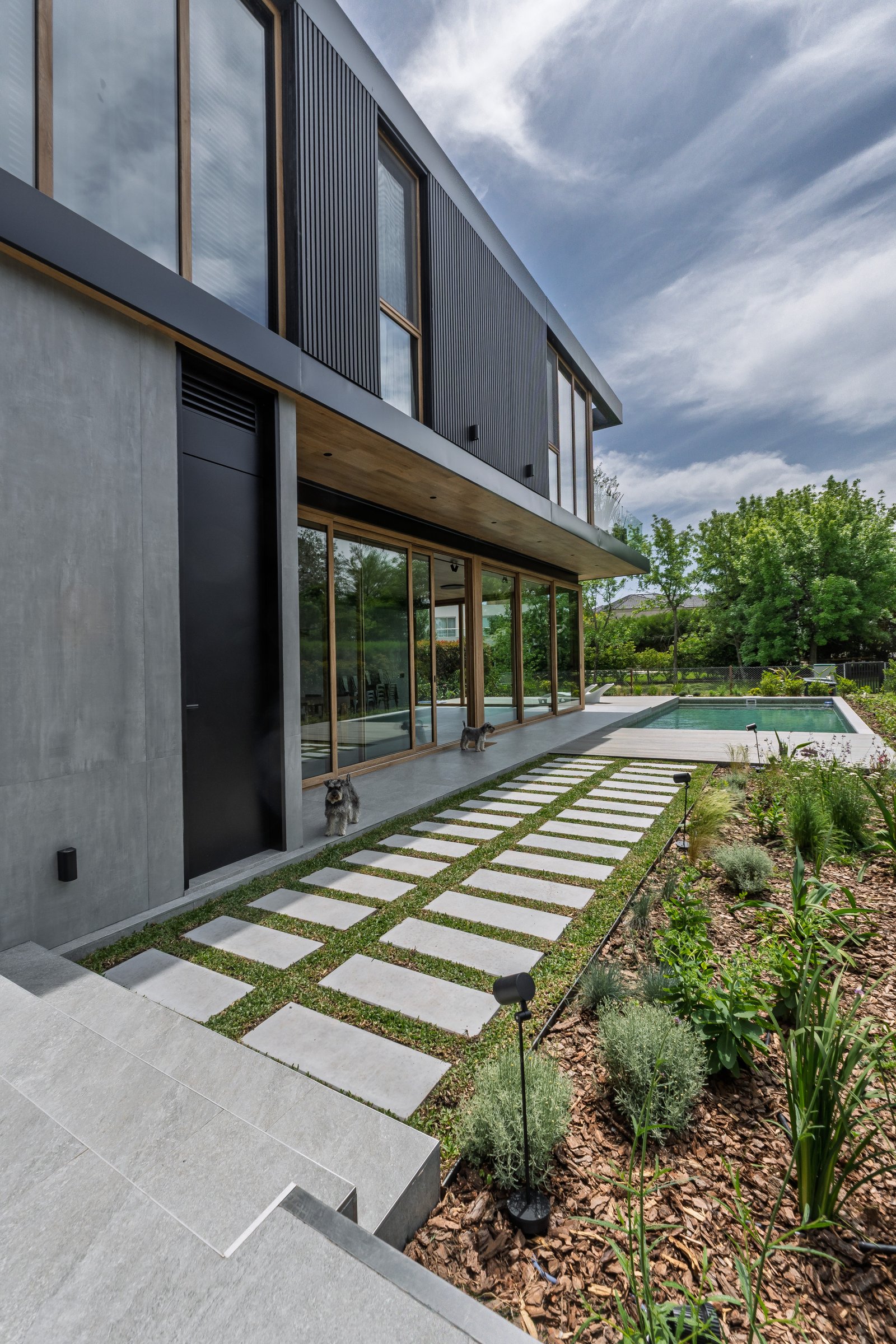 Casa moderna com fachada de concreto e metal, jardim e piscina — projeto Castores - Estudio Gambotto, por ABEJA CONCEPT, em Los Castores