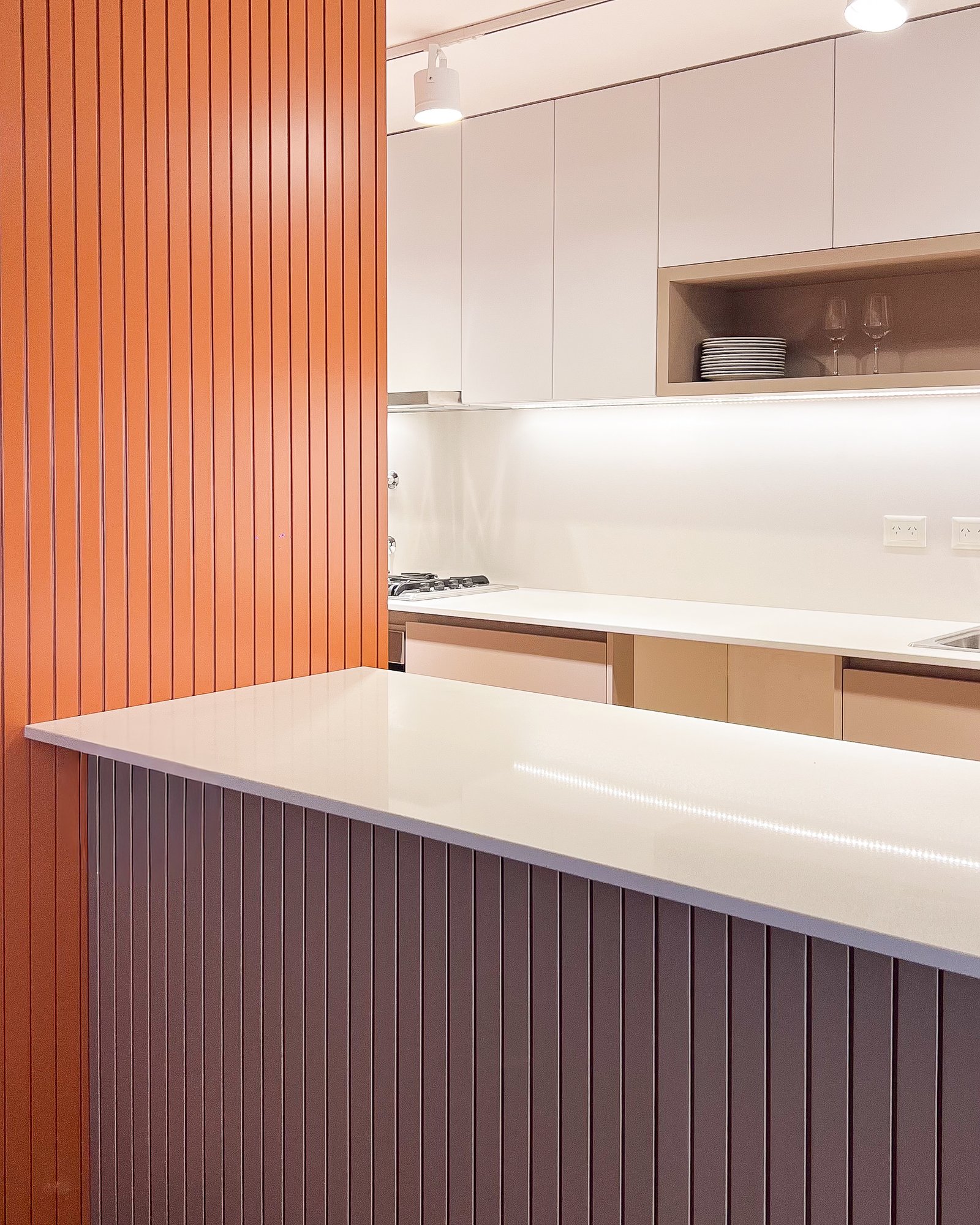 Cozinha moderna com ilha e painéis de madeira laranja e branca — projeto REFORMA O, por Rastro Estudio, em Mar del Plata