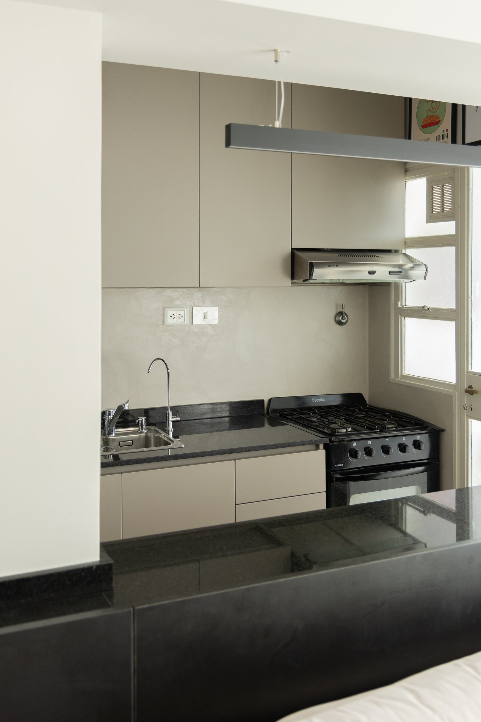 Cozinha moderna com armários em taupe e bancada preta — projeto Arcos, por cromo., em Belgrano