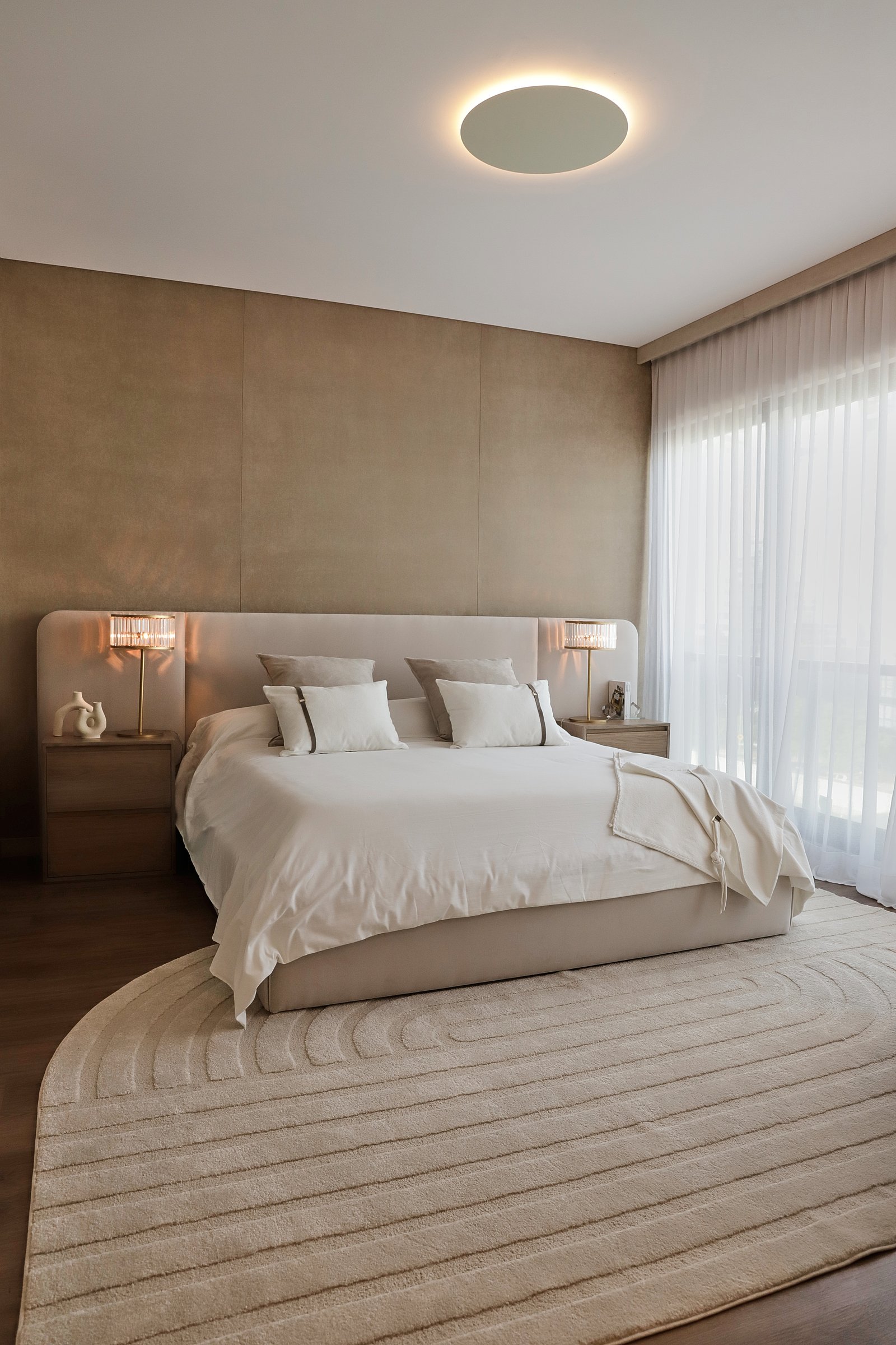 Dormitorio moderno minimalista con cama grande, paredes de piedra beige y luz indirecta — proyecto OBRA TORRES LINK, por MARCELO MAZZA, en Puerto Madero