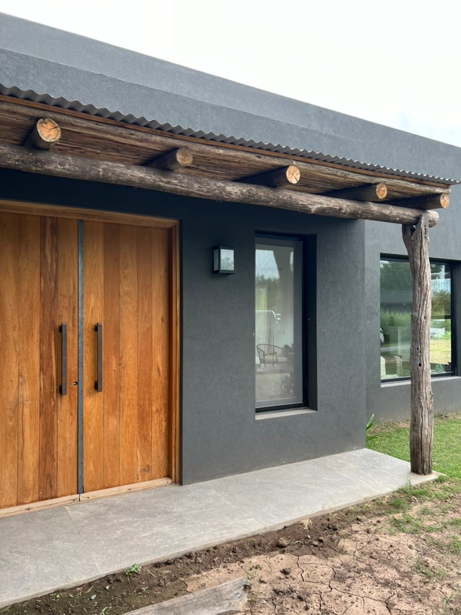 Fachada moderna con pérgola rústica y puertas de madera — proyecto CASA RZ, por SEDE Arq., en Pilar