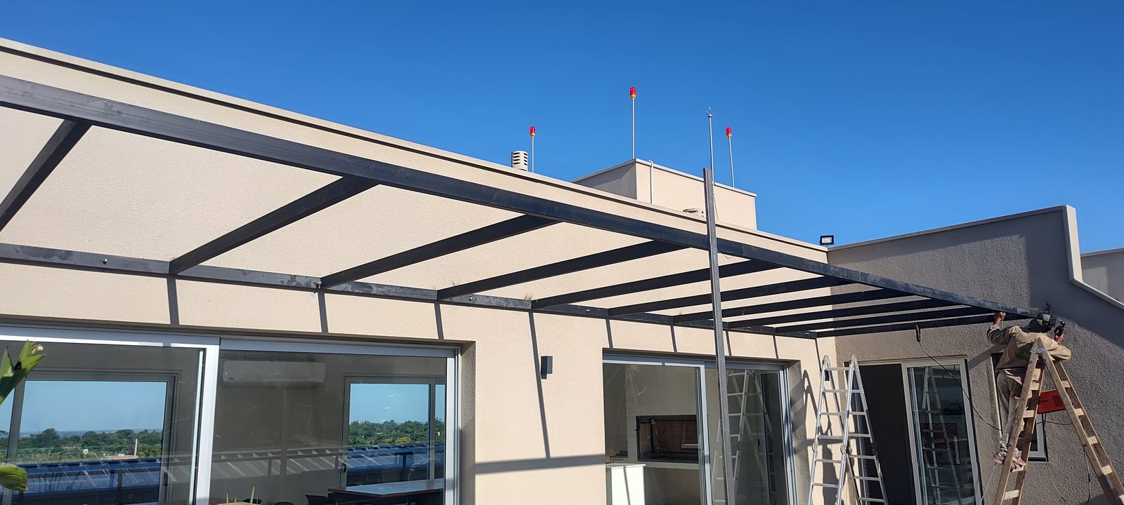 Terraza en construcción con pérgola moderna y vista urbana — proyecto EDIFICIO CHUBUT, por HMCONSTRUCCIONES, en Chubut
