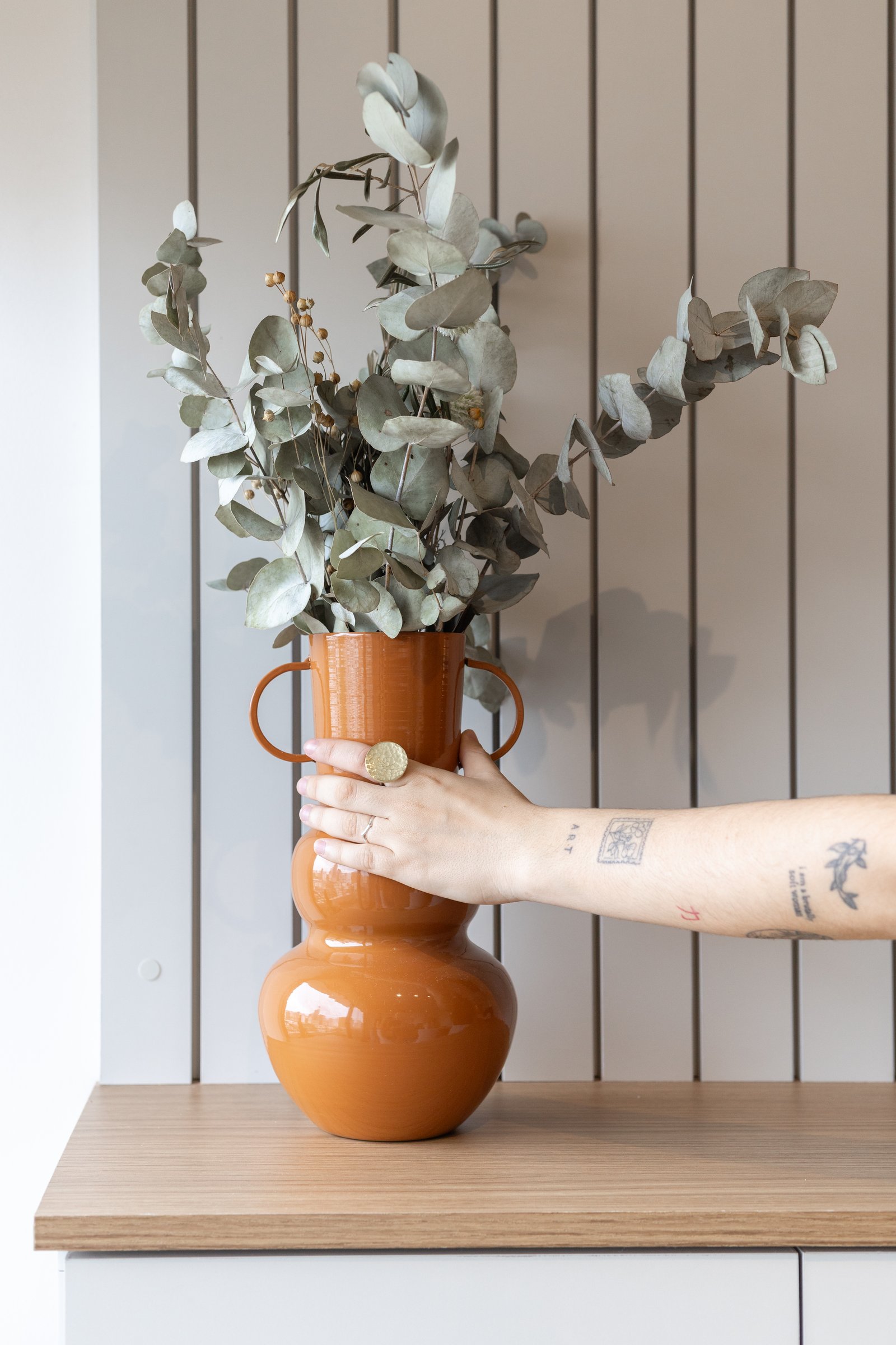 Jarrón terracota con eucalipto seco sobre pared de madera — proyecto Rio, por Martina Kleinert, en Saavedra