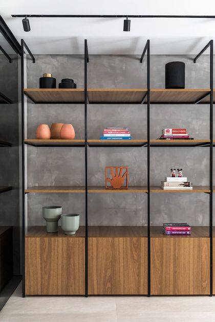 Estante con estructura metálica negra y madera en pared de hormigón — proyecto Bidese Recepcao, por Boscardin Corsi Arquitetura