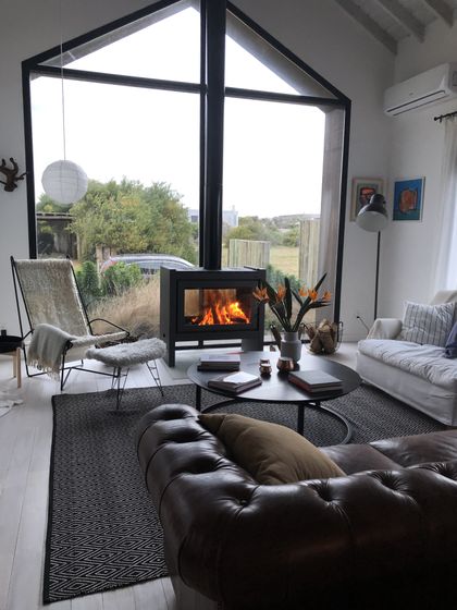Living moderno con hogar integrado, sillón cuero negro y vista exterior — proyecto JI 103, por Estudio Diez Muzzio