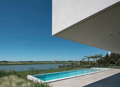Piscina moderna con deck de hormigón y vista al agua — proyecto Casa Lombardi, por Estudio Ramos