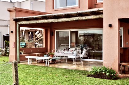Galería moderna con pérgola de madera y living exterior con sillones y mesita — proyecto Santa Teresa, Villanueva, por Marconi Silva Arquitectos, en Benavidez