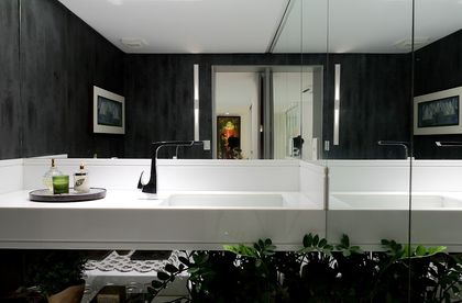 Baño minimalista con mesada doble blanca, espejos iluminados y plantas — proyecto Apartamento 250m em Casa Forte, por André Caricio
