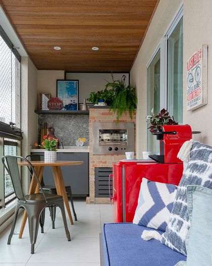 Quincho moderno con parrilla roja, techo madera y plantas colgantes — proyecto Apartamento Nóbrega, por Amanda Miranda