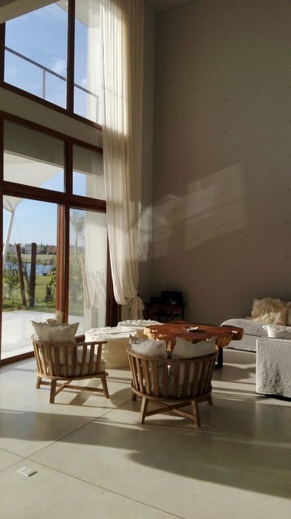 Terraza luminosa con sillones de madera y vista al exterior — proyecto SG-01, por VGLA Arquitectos, en Dique Luján