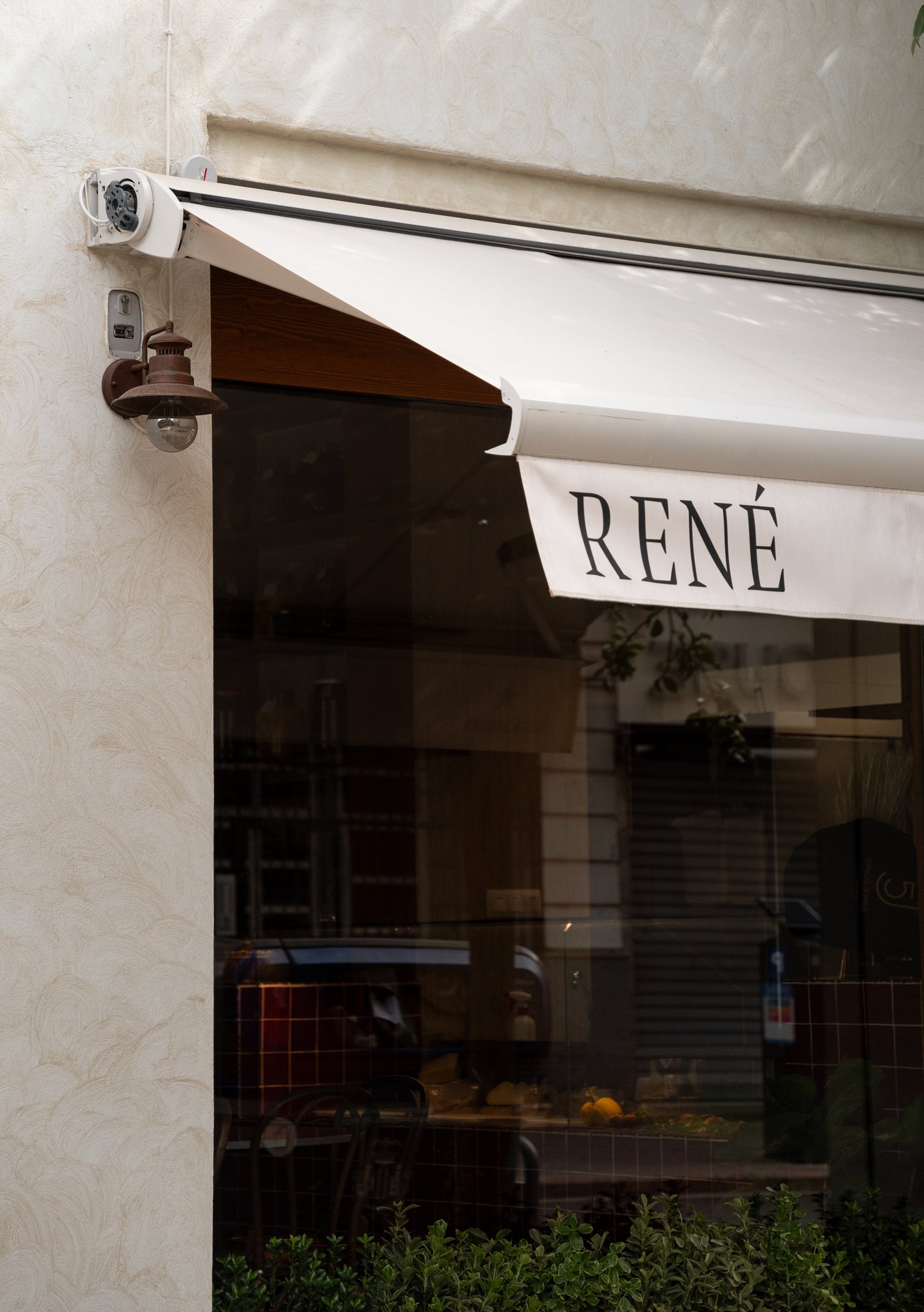 Fachada de loja comercial com toldo e placa 'René' — projeto René Restaurant, por JT ARQUITECTURA, em Valencia