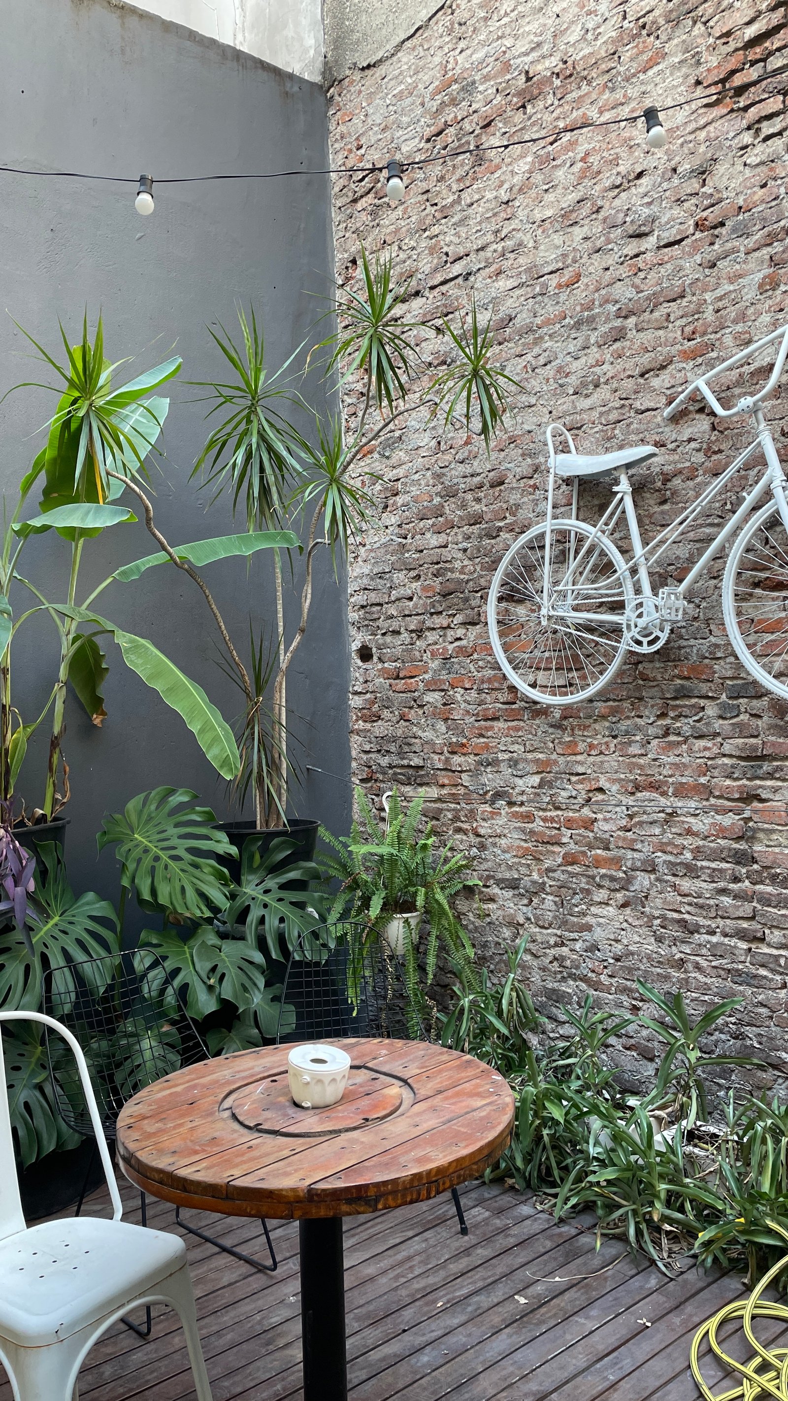 Pátio rústico com bicicleta pendurada e mesa de carretel — projeto Espacio BALVAN, por DE DIOS Estudio, em Balvanera