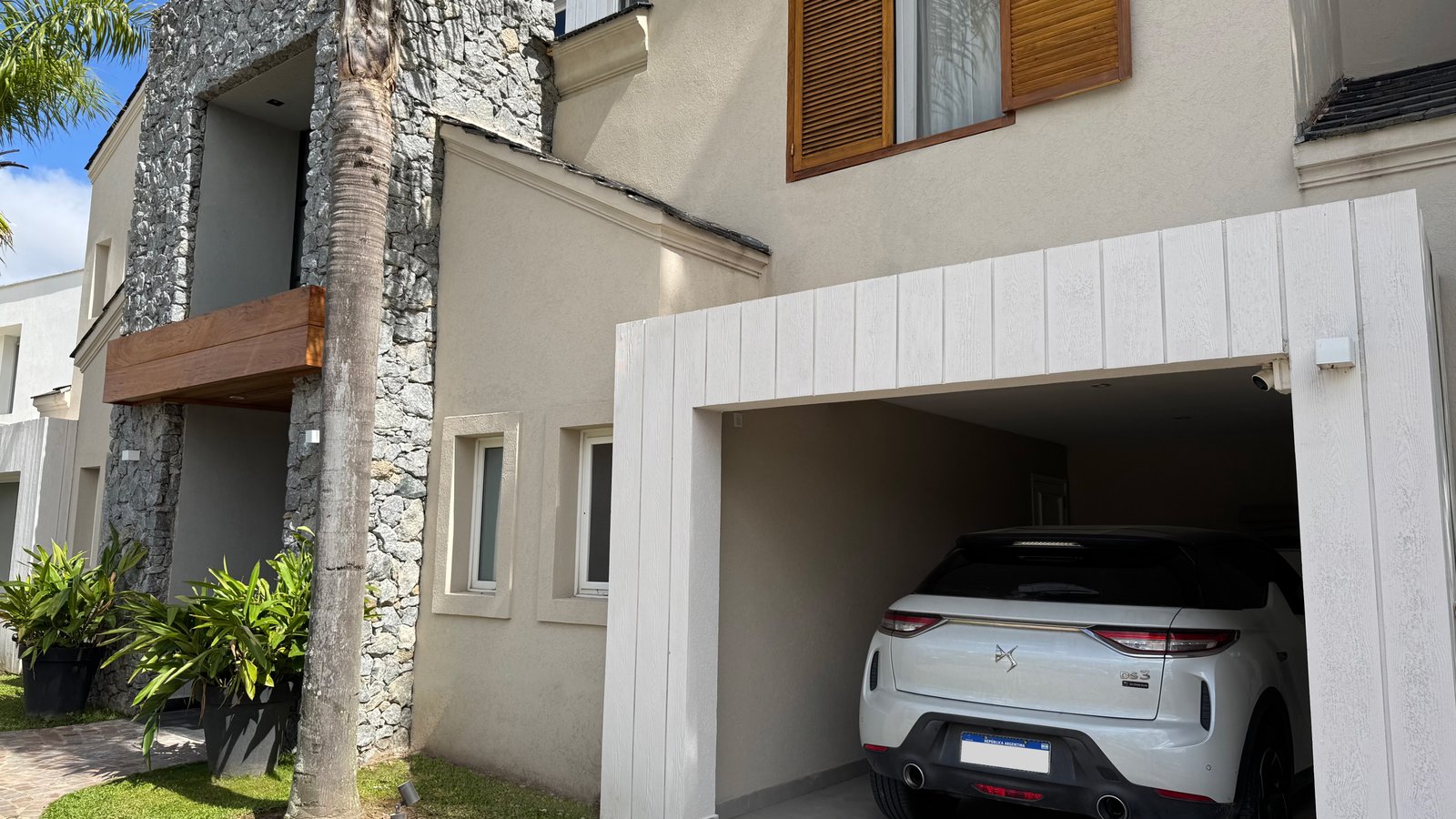 fachada moderna con garage integrado y jardín — proyecto CASA CM, por Hermann Arquitectos, en Los Castores