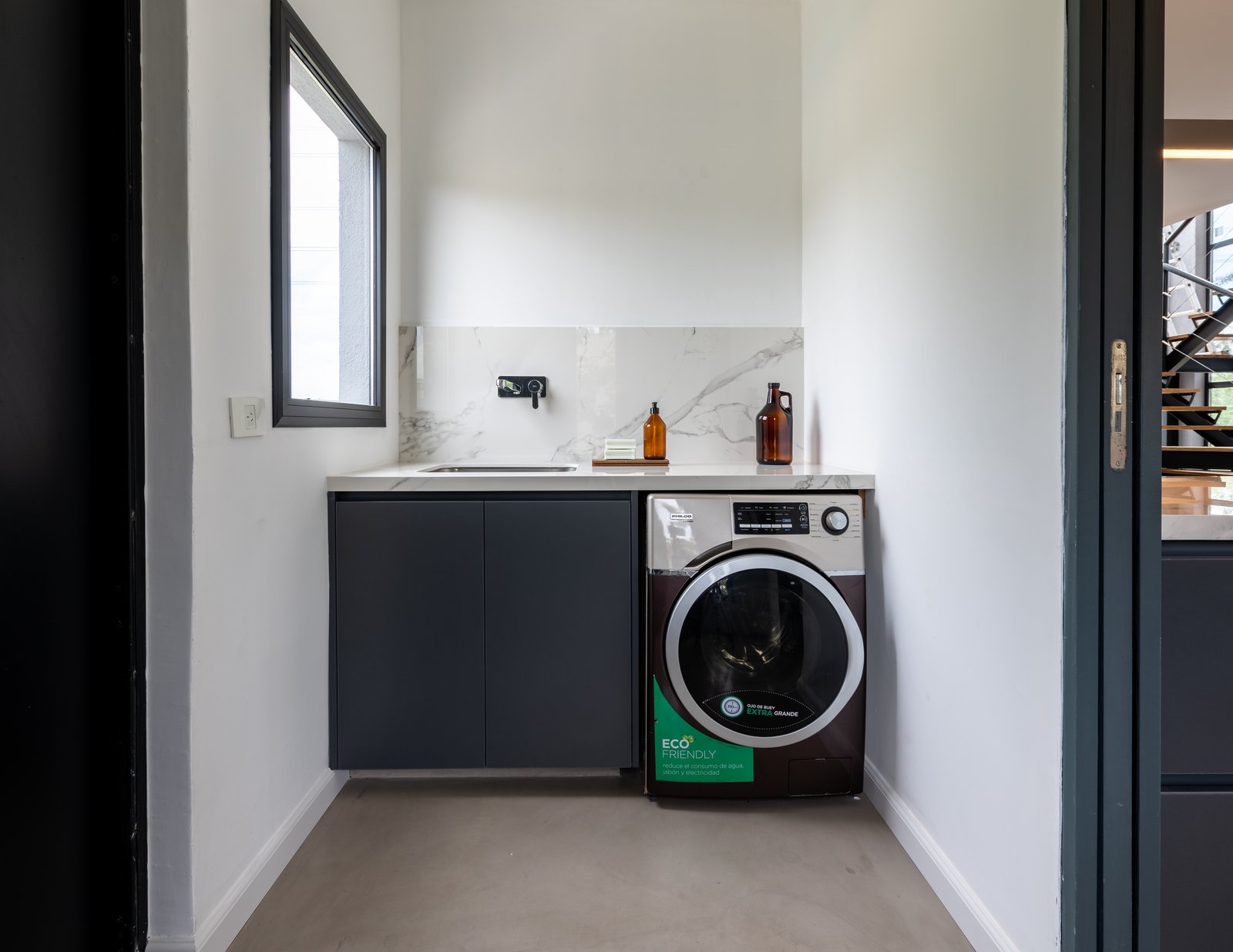 Lavadero moderno con muebles grises y lavadora — proyecto Santa Isabel - Andrea Gonzalez, por ABEJA CONCEPT, en Nordelta