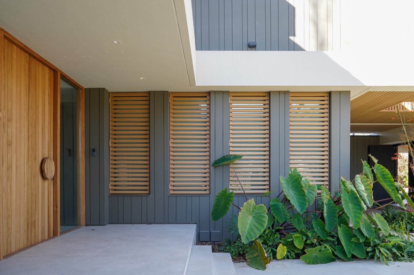 Fachada moderna con revestimiento de madera y vegetación exuberante — proyecto Obra Torterola, por lifecycle, en Provincia de Buenos Aires