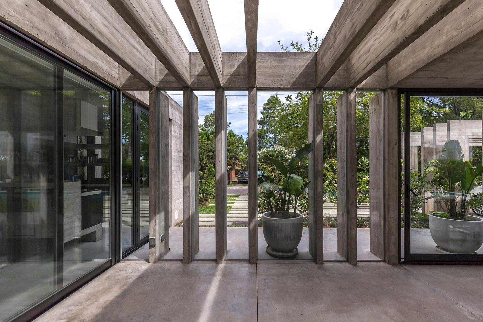Espaço brutalista com concreto aparente e vegetação — projeto Casa Aranzazu, por Besonías Almeida arquitectos, em B1667 Tortuguitas