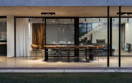 Comedor moderno con grandes ventanales, muebles de madera y piso de hormigon — proyecto Horizon House, por Estudio UFV72, en B2814 Los Cardales