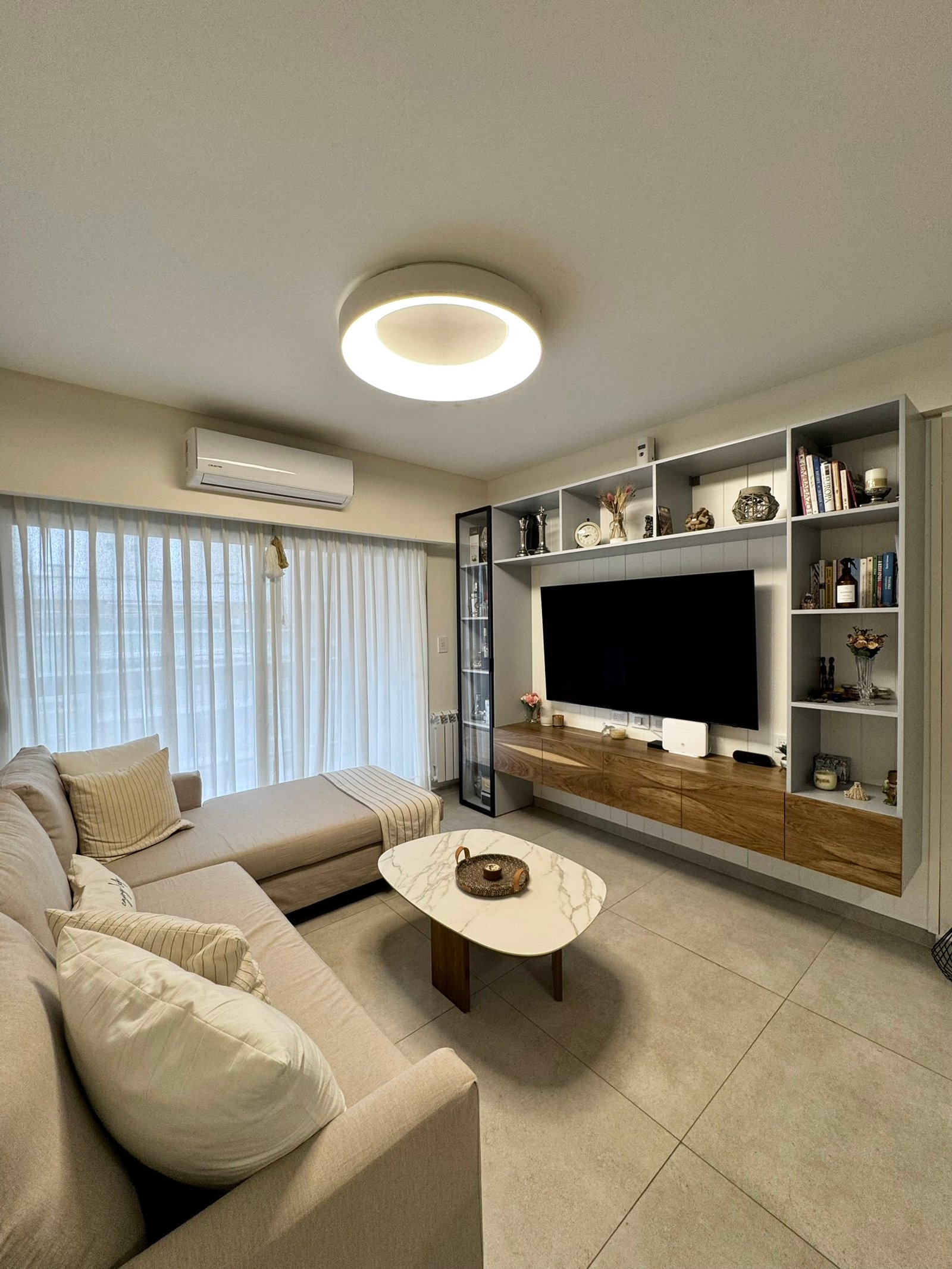 Living moderno con sofá seccional y mesa de mármol oval — proyecto Corrientes I, por MDBK Arquitectura, en Villa Crespo