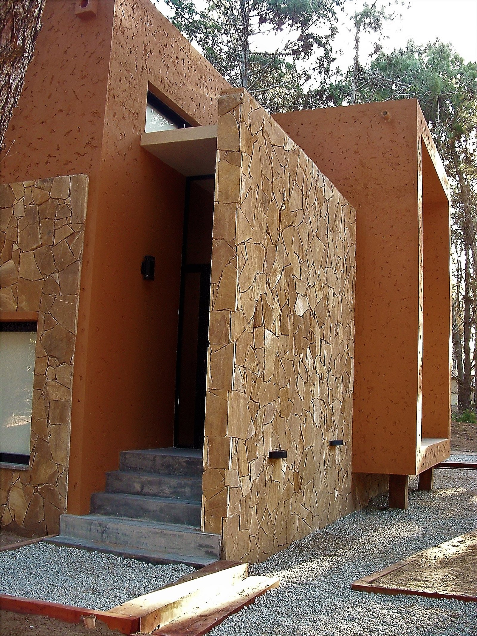 Fachada moderna con piedra irregular y estuco terracota — proyecto LA  ALHAMBRA, por GJF estudio, en Costa del Este
