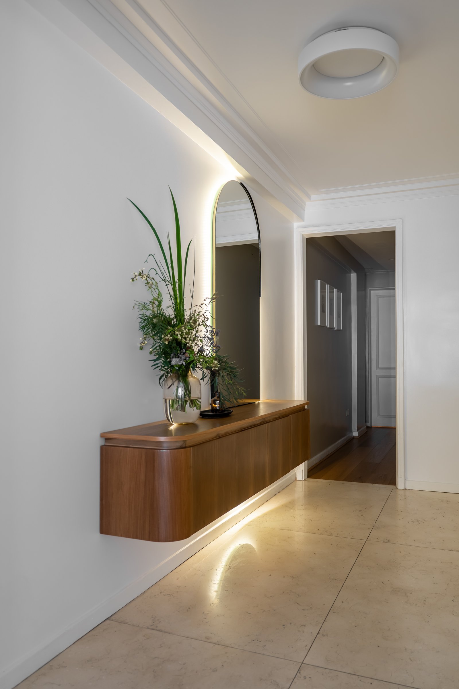Pasillo moderno con mueble flotante de madera y espejo arqueado — proyecto Rodriguez Peña , por BK Arquitectos, en Recoleta
