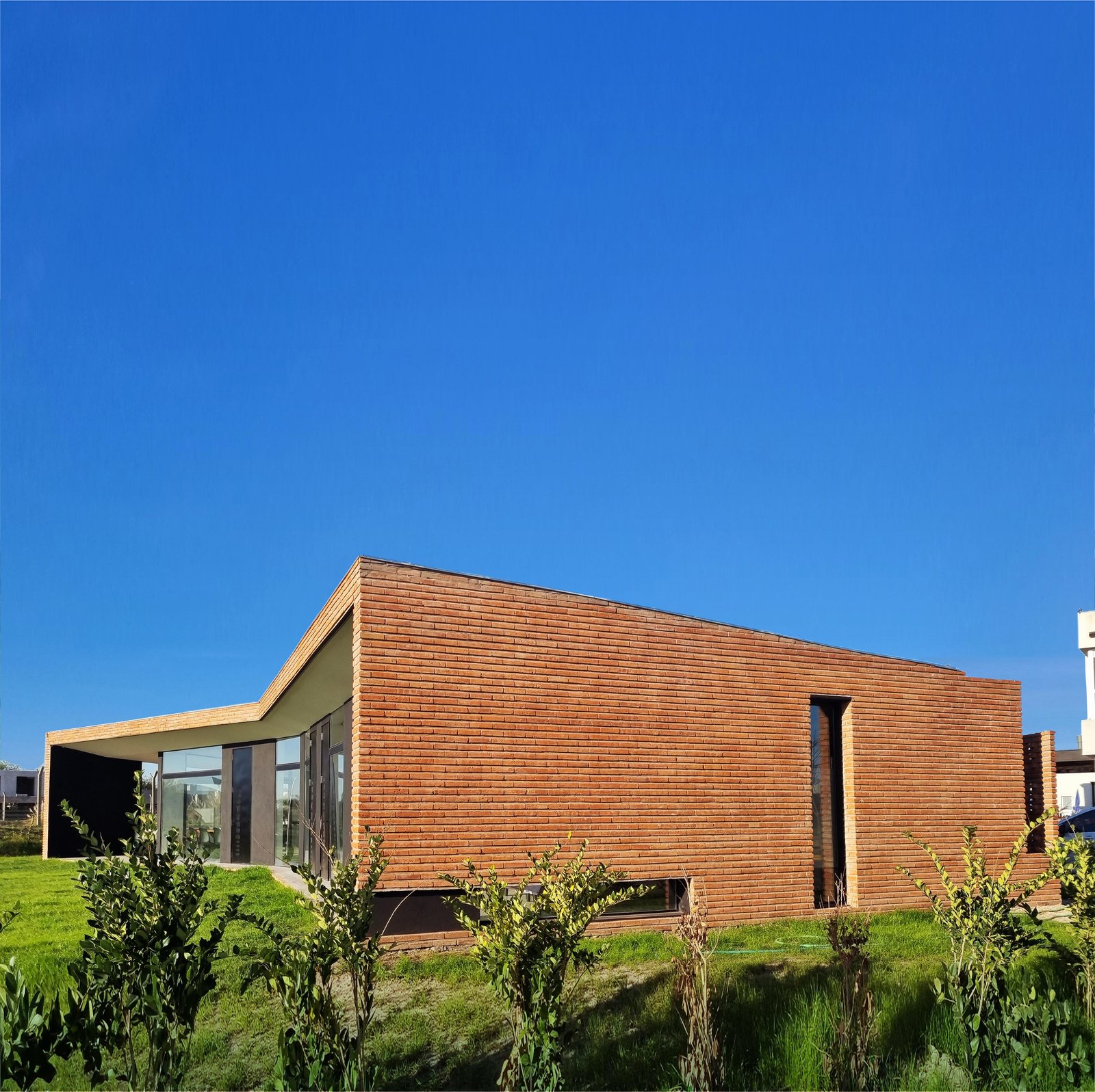 Fachada moderna de ladrillo angular con grandes ventanales — proyecto SS01-House, por Etunez, en Provincia de Buenos Aires