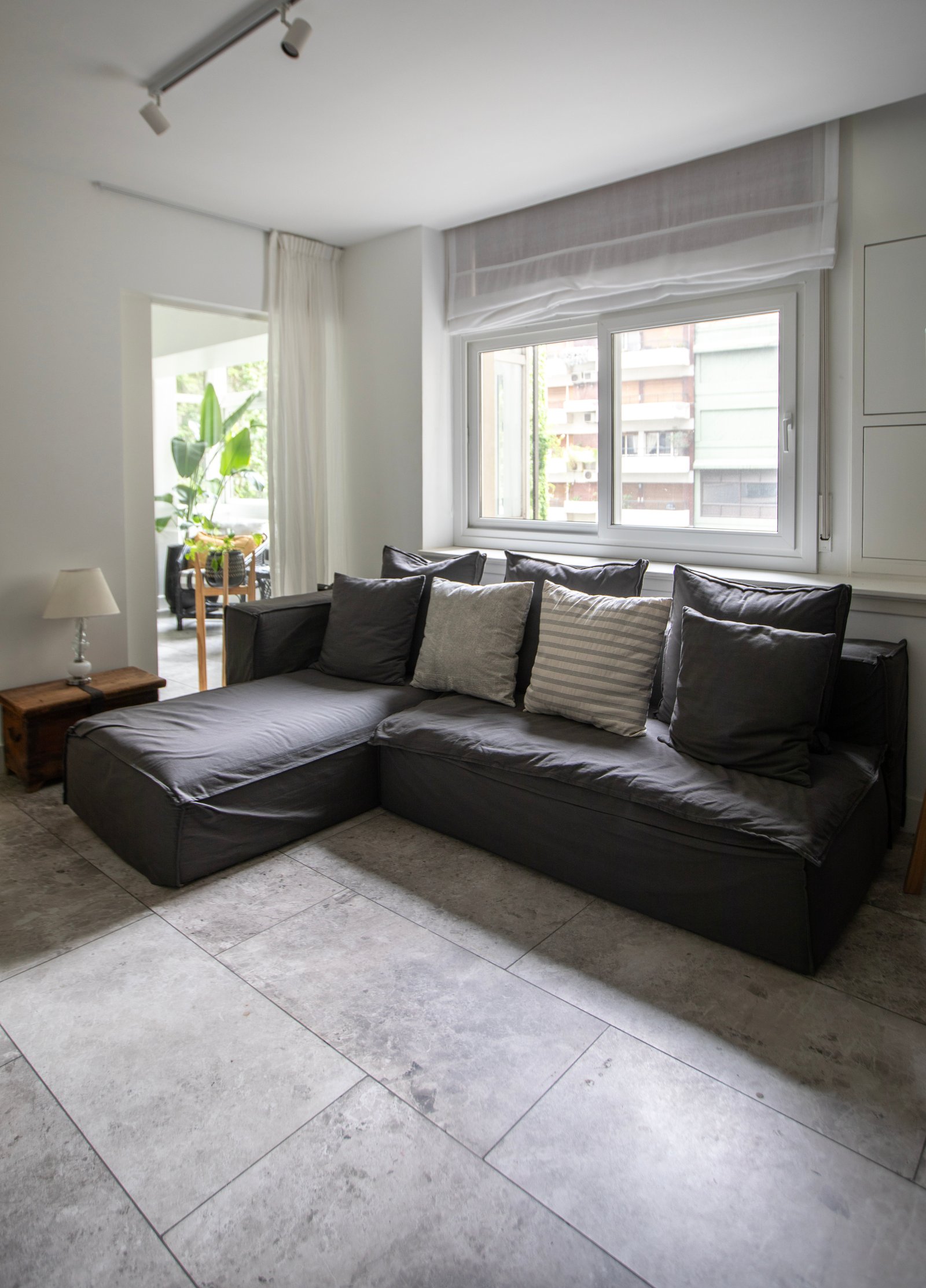 Sala de estar moderna com sofá seccional cinza e piso de pedra — projeto PROYECTO PARQ, por ILVA, em Provincia de Buenos Aires