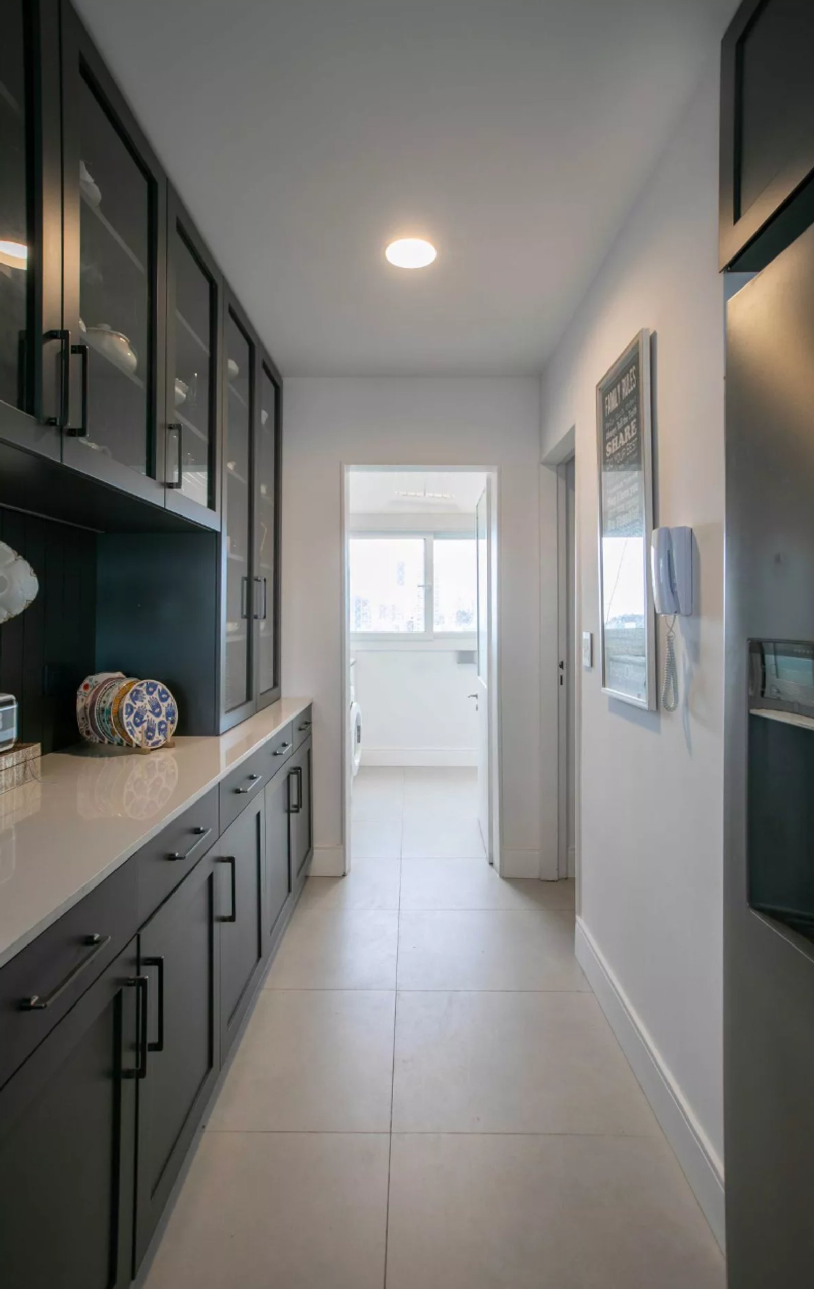 Pasillo moderno con muebles oscuros y acceso a lavadero — proyecto Elevando el Estilo: Terminaciones que resaltan los ambientes., por ATRIM GLOBAL, en Provincia de Buenos Aires