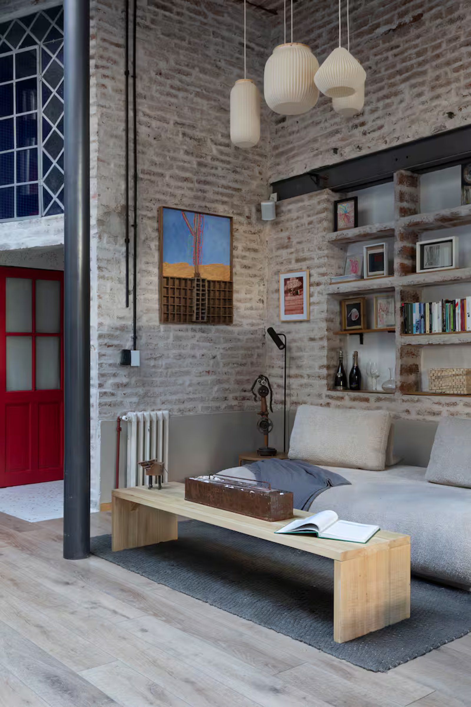Sala de estar industrial con ladrillos expuestos y lámparas colgantes — proyecto Casa Arcos, por Silvia Soqueff, en Núñez