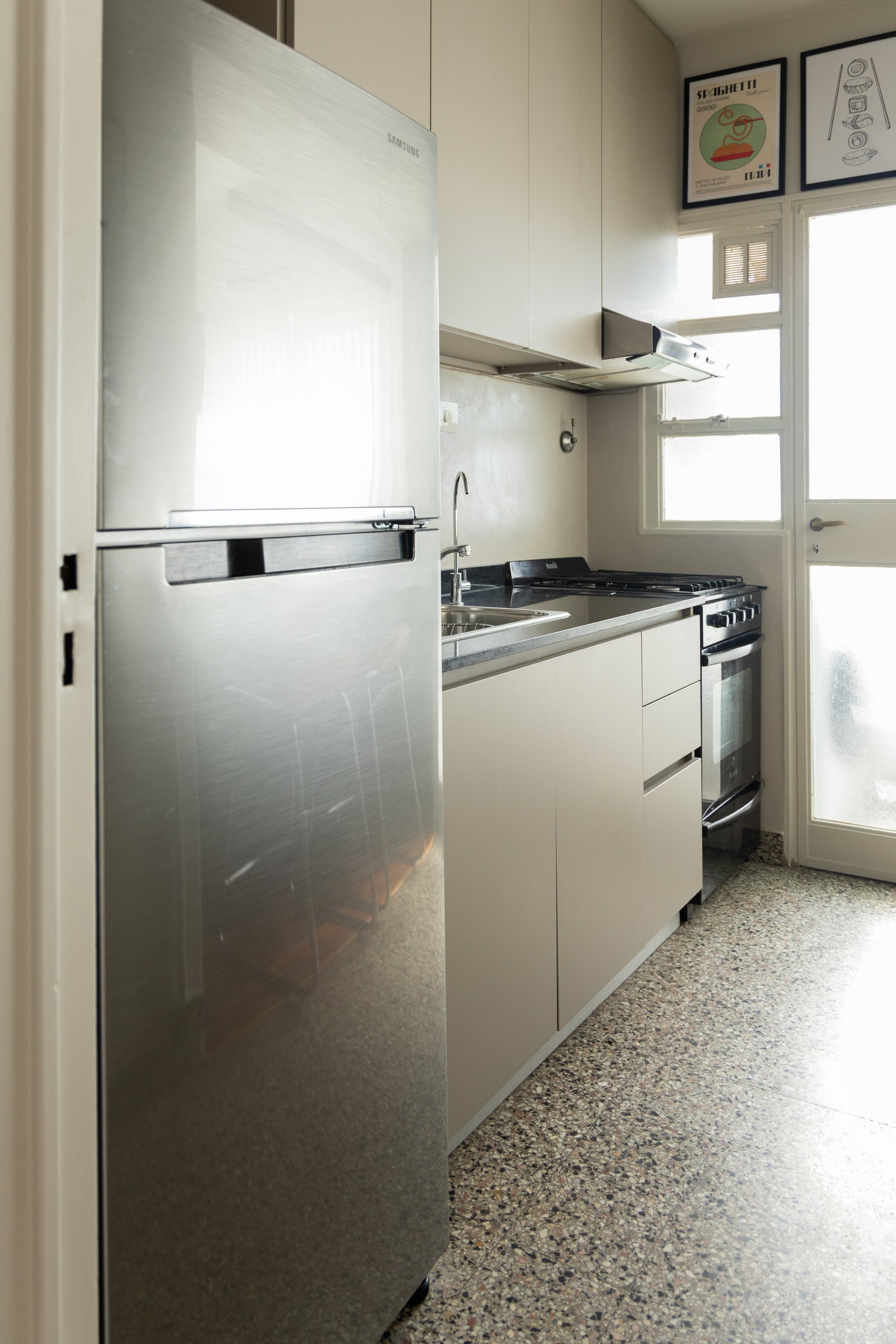 Cocina moderna con heladera de acero inoxidable y suelo de terrazo — proyecto Arcos, por cromo., en Belgrano