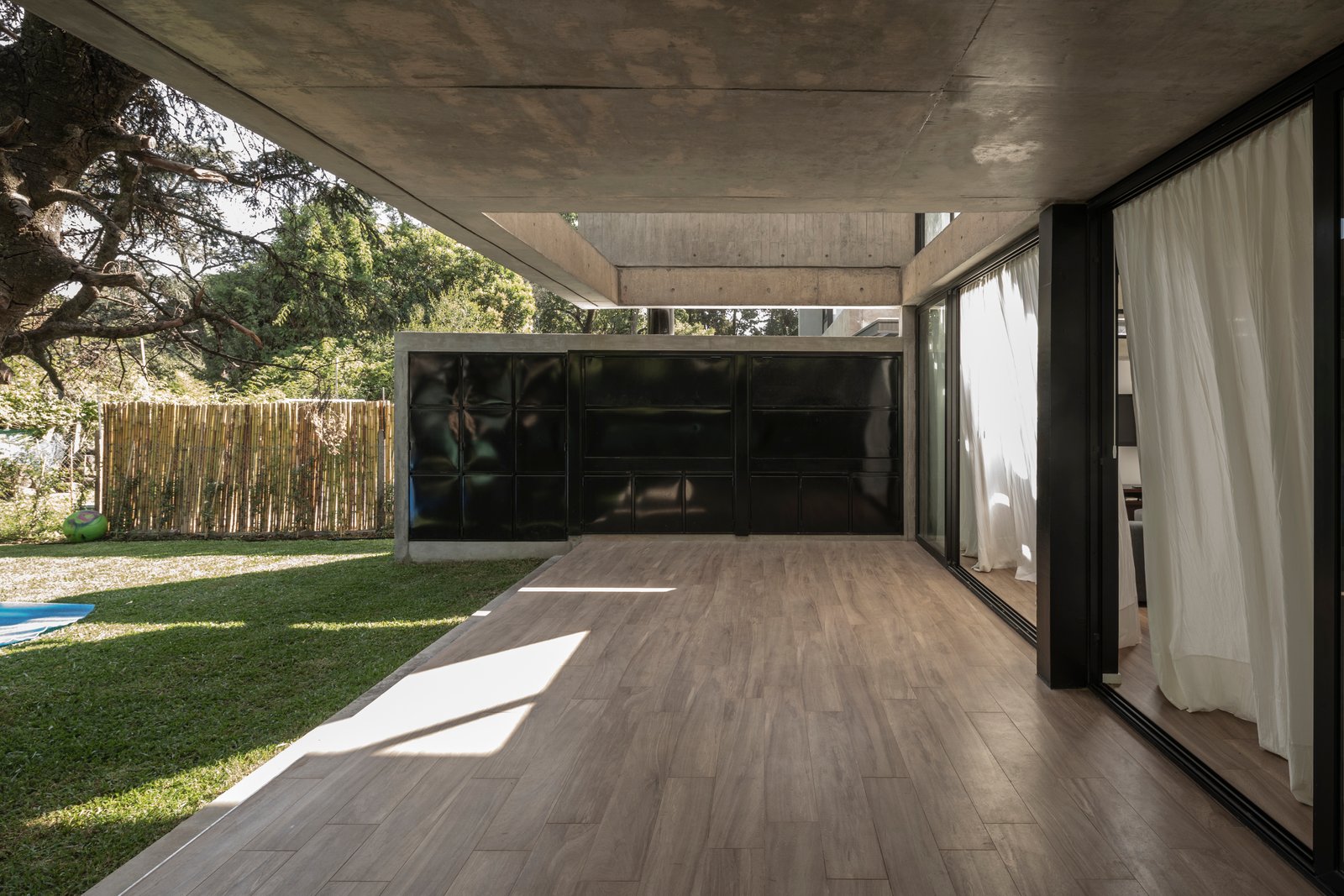 varanda moderna com deck de madeira e janelas grandes — projeto Casa Emilia, por Grupo CRBN, em Parque Leloir