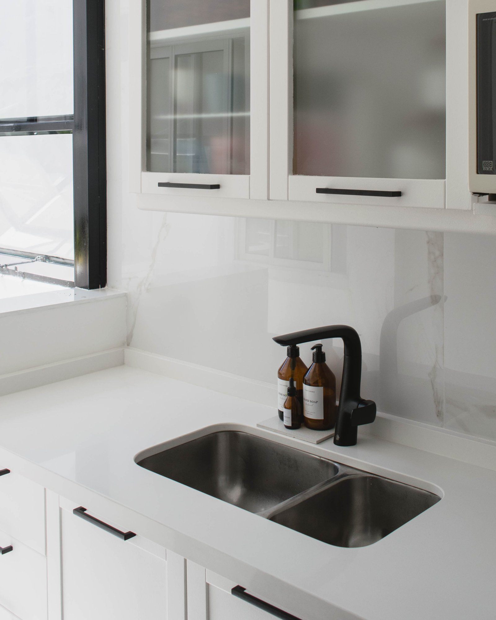 Cocina moderna con mesada de piedra blanca y grifería negra — proyecto Goyena, por Martina Kleinert, en Caballito