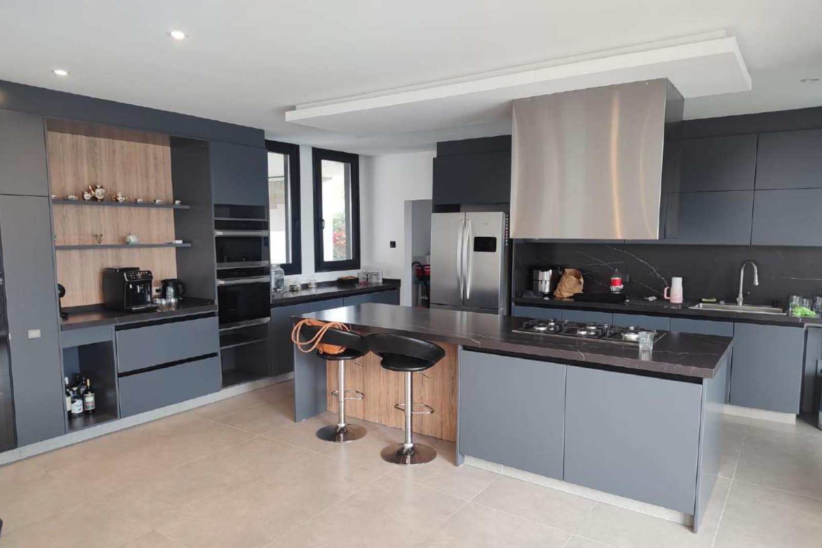 Cocina moderna gris con isla central y bancos rojos — proyecto Vivienda Laggon, por MMCZ STUDIO, en R. Caamaño 1106