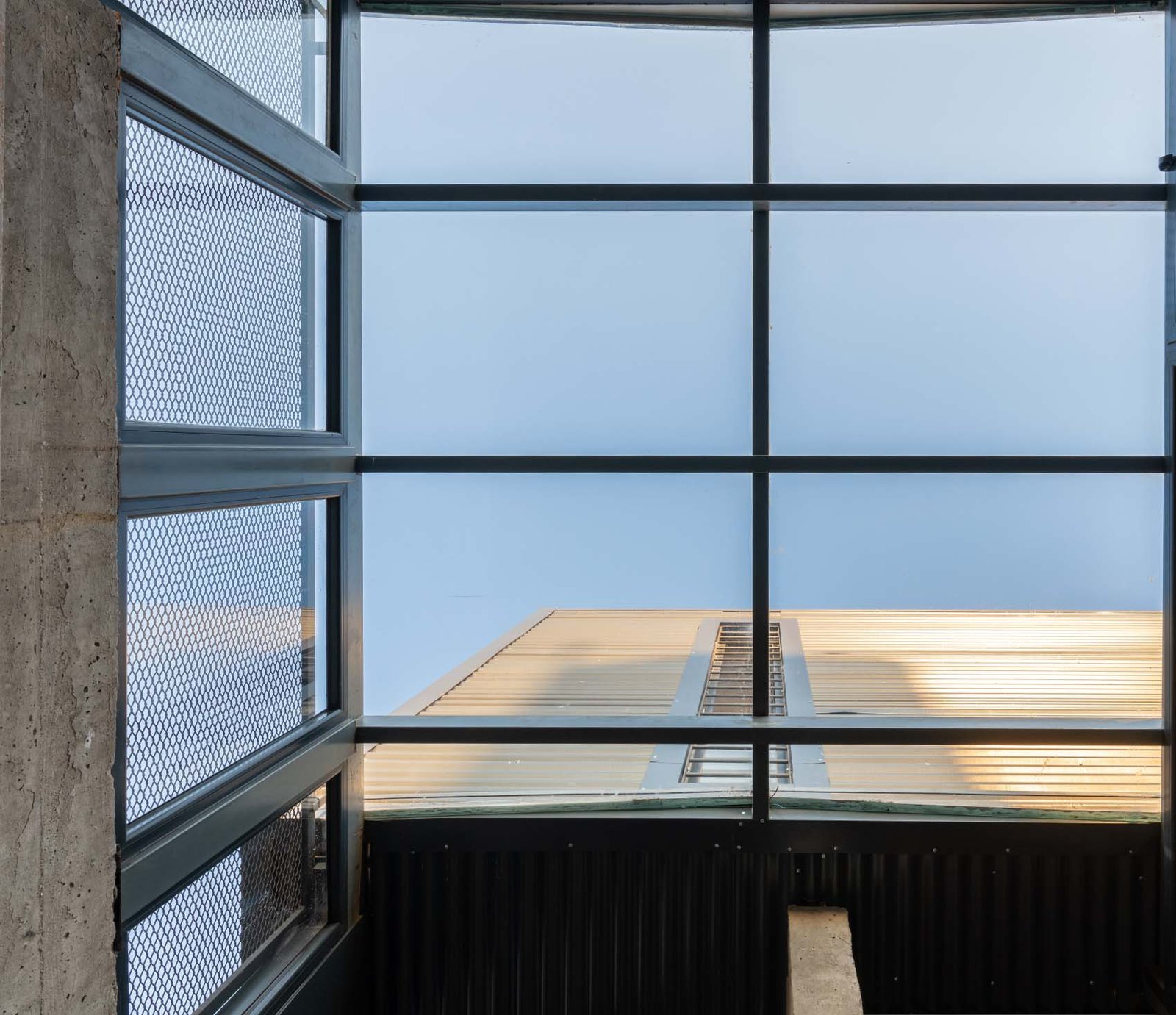 Ventana industrial con cielo azul y detalles de hormigón — proyecto CASA URRUTIA, por Sol Blanc. arquitecta, en Córdoba