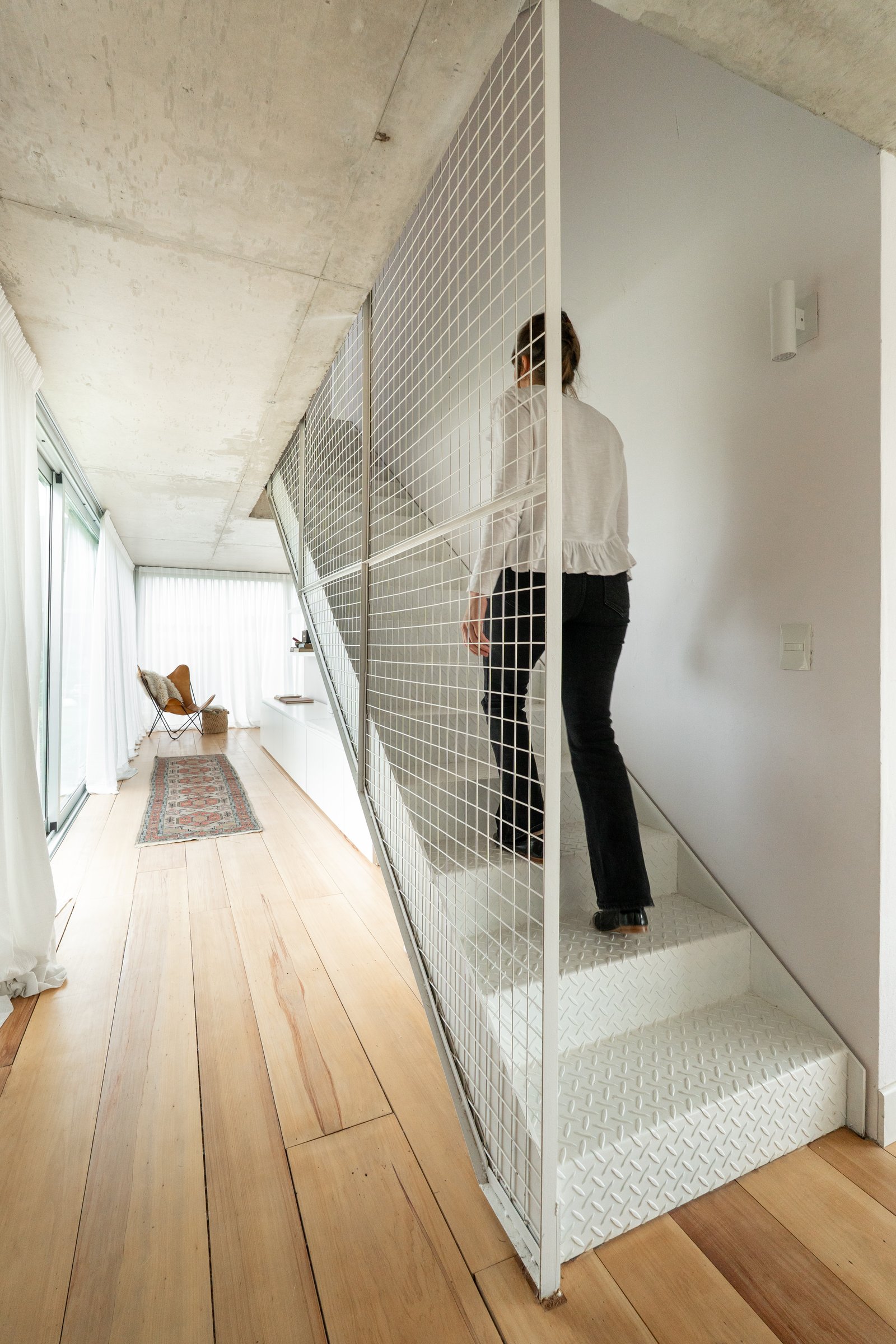 Corredor moderno com escada de metal e piso de madeira — projeto Carpinchos, por LACROZE DESIGN STUDIO, em Nordelta
