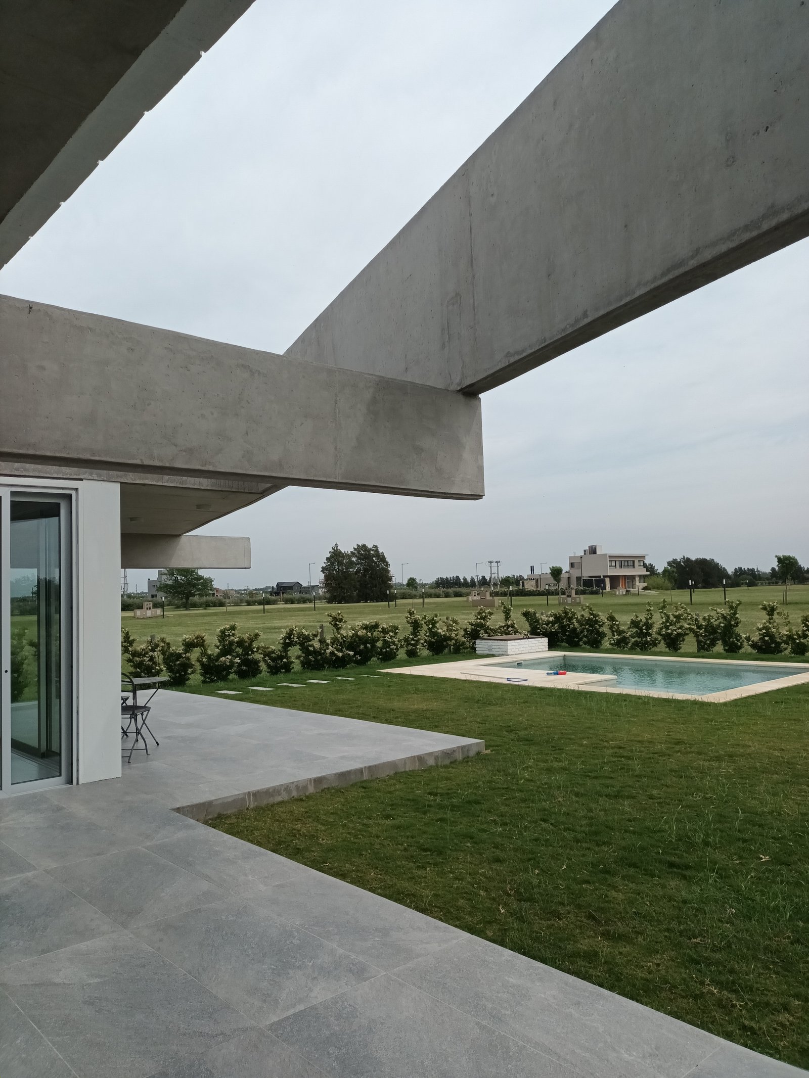 Área de piscina moderna com vigas de concreto aparente — projeto CASA AA, por DIB OBRIST Arquitectas, em Ing. León Miglierini 600