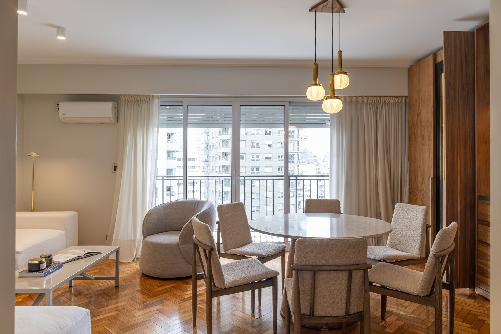 Comedor moderno con mesa redonda, sillas beige y luces colgantes — proyecto LIBERTADOR DANDY, por AB ARQUITECTURA, en Recoleta